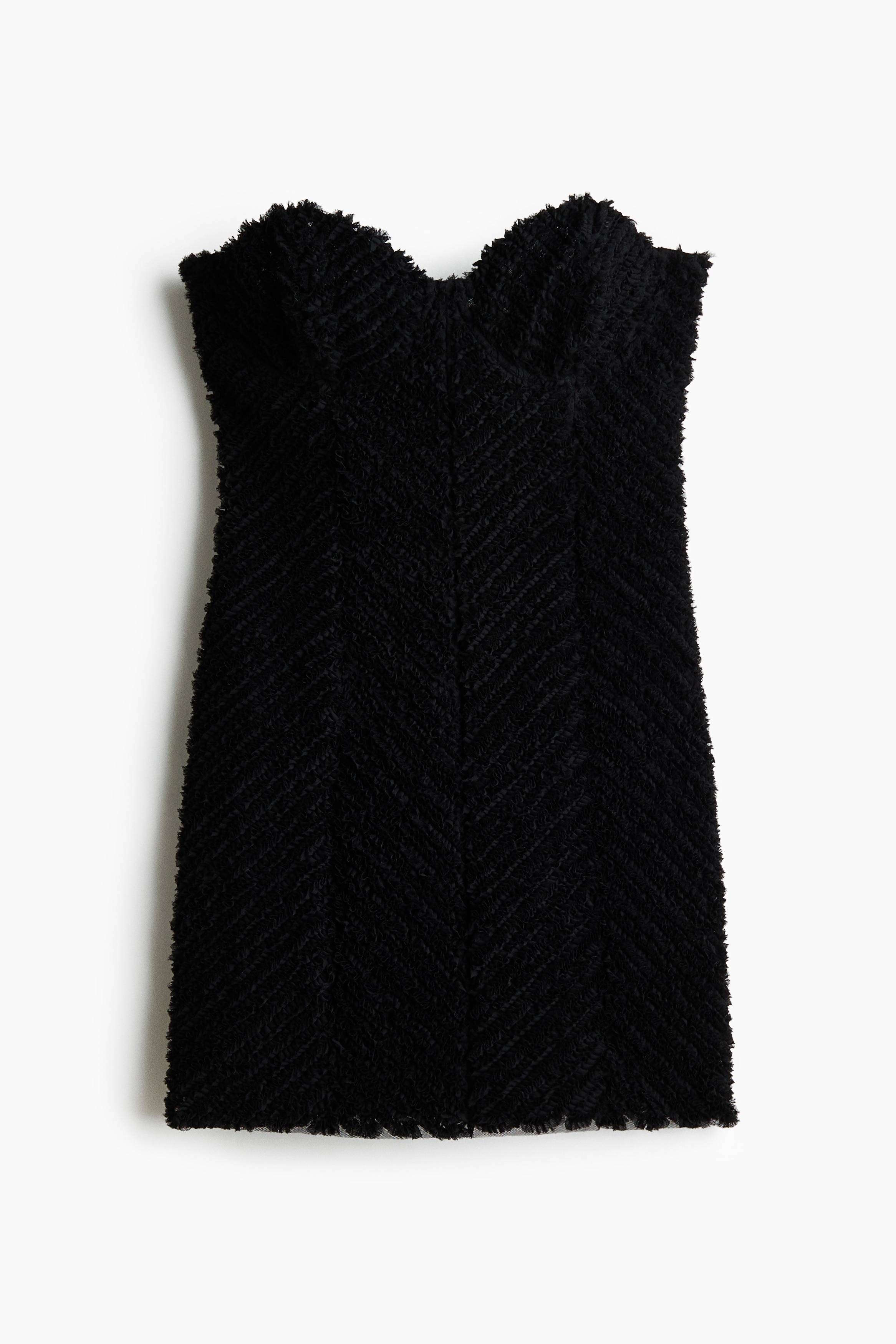 La modelo lleva un minivestido negro sin tirantes con escote corazÃ³n y tejido texturizado con estampado. El vestido entallado se combina con gafas de sol oscuras, medias negras y anillos plateados.