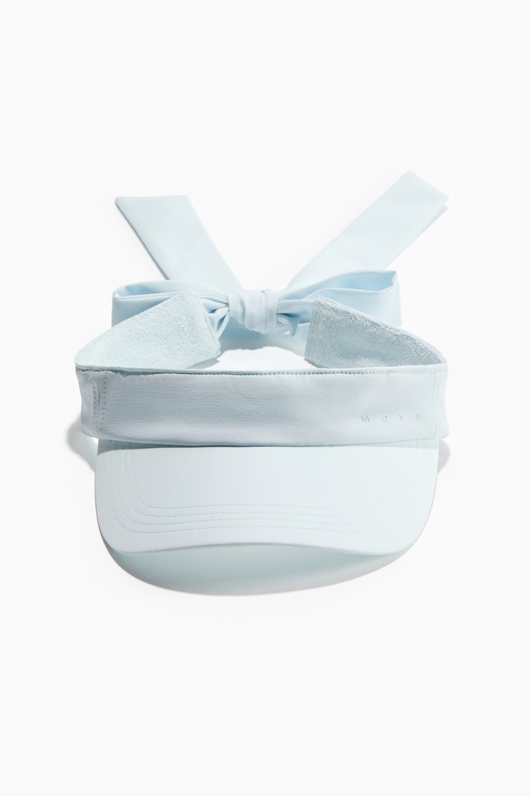 View larger image: A light blue visor is facing front, featuring a curved brim with visible stitching. A wide headband is displaying the embossed word 'MOVE' on its right side, and two long fabric ties are forming a bow at the back with textured ends.