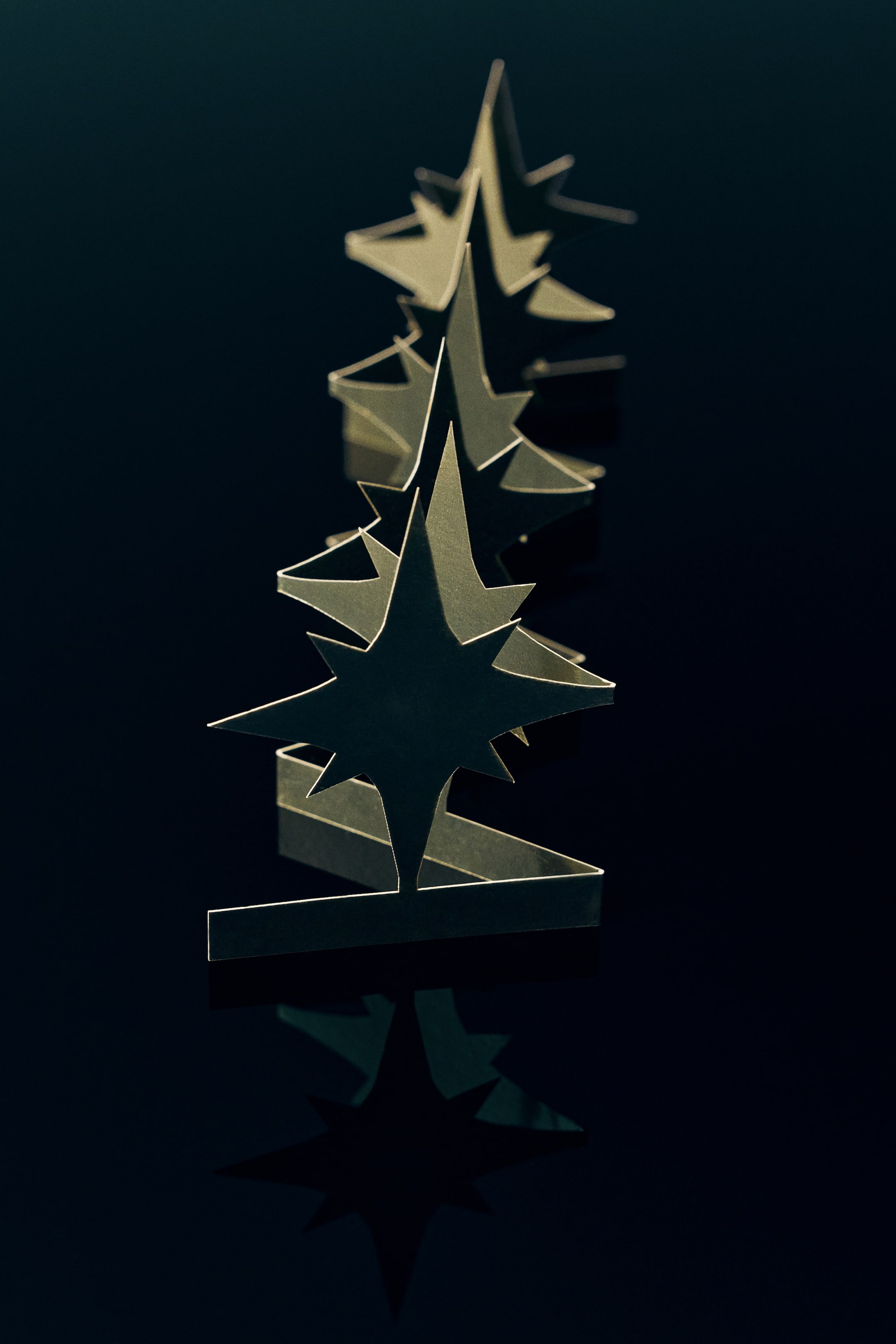 Ver imagen más grande: Un adorno navideño de papel con diseño desplegable muestra una serie de formas de estrella verticales e interconectadas, unidas a lo largo de una base de acordeón en zigzag. Las estrellas de papel de color claro se extienden hacia atrás para crear una decoración festiva tridimensional e independiente.