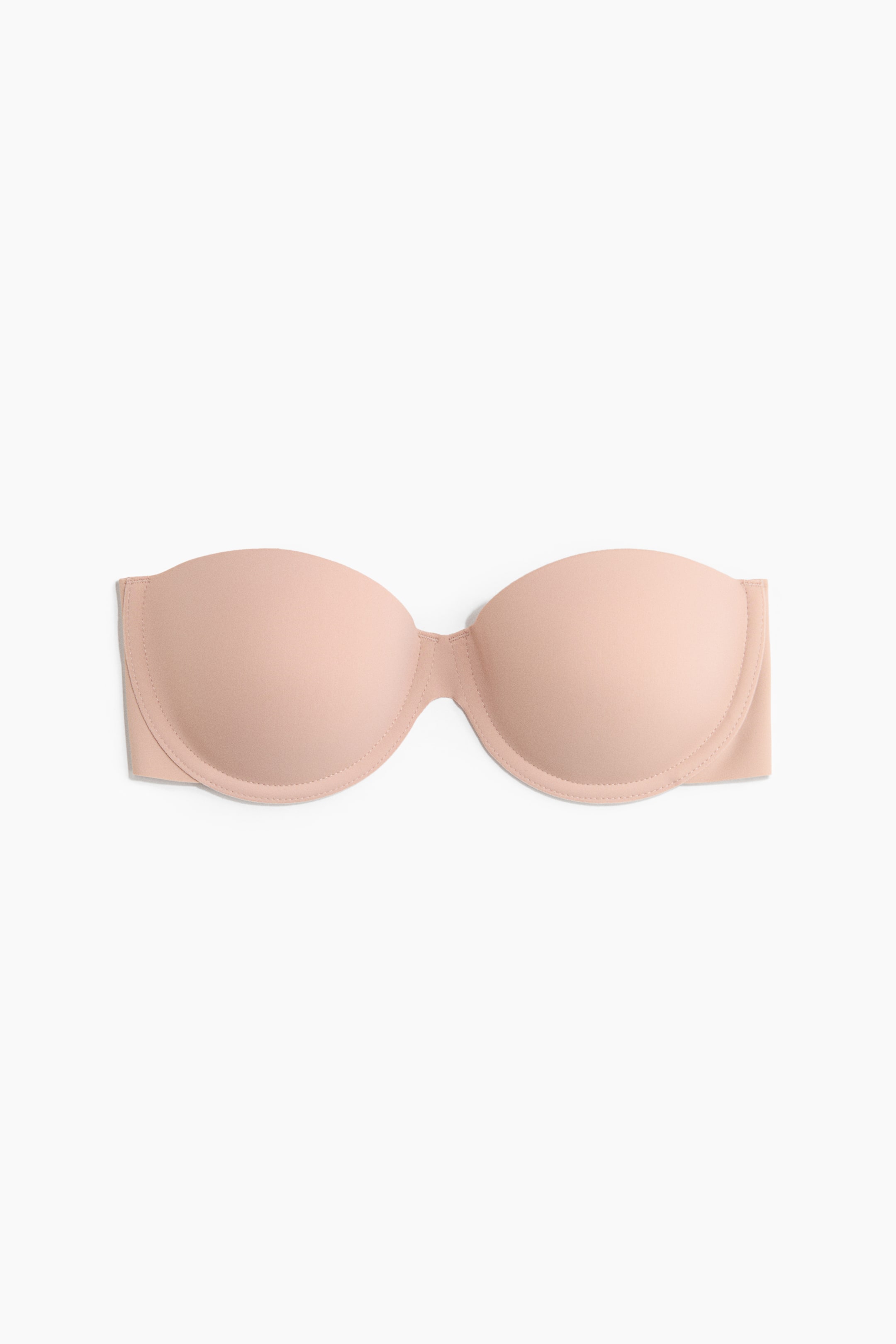 Agrandir l'image: Un soutien-gorge auto-adhésif en microfibre beige clair est posé à plat, présentant sa vue de face. Deux bonnets légèrement rembourrés et à armatures façonnent le buste et offrent un soutien, avec les côtés s'étendant vers l'extérieur, indiquant un design sans bretelles ni dos.
