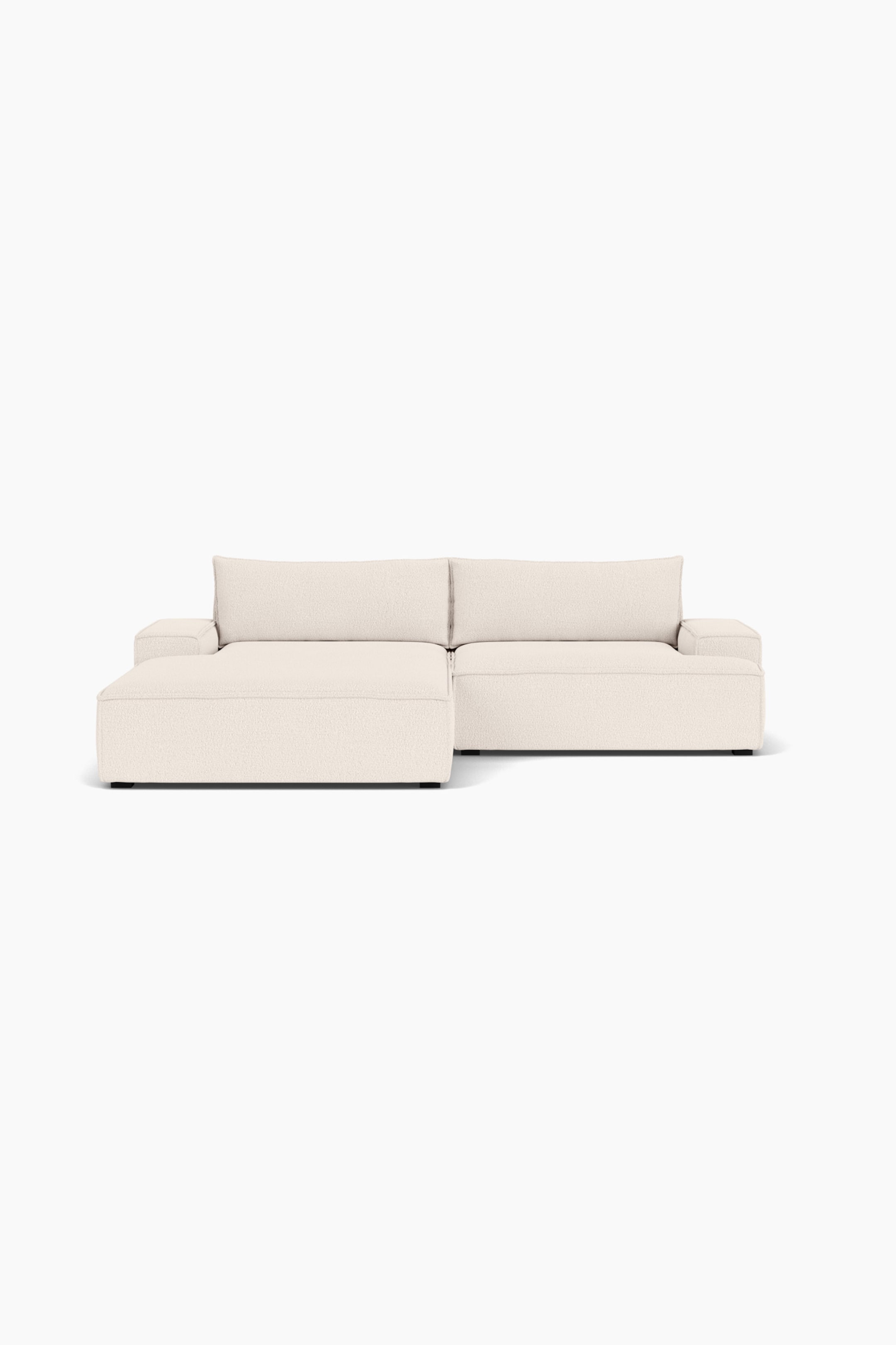 Größeres Bild ansehen: Ein frontal aufgenommenes, cremefarbenes modulares Ecksofa ist zu sehen, mit einer breiten Chaiselongue auf der linken Seite und einem Standardsitz auf der rechten Seite. Das flache Design ist mit einem strukturierten Stoff bezogen und verfügt über breite Armlehnen, zwei große Rückenkissen und dezente dunkle Füße.