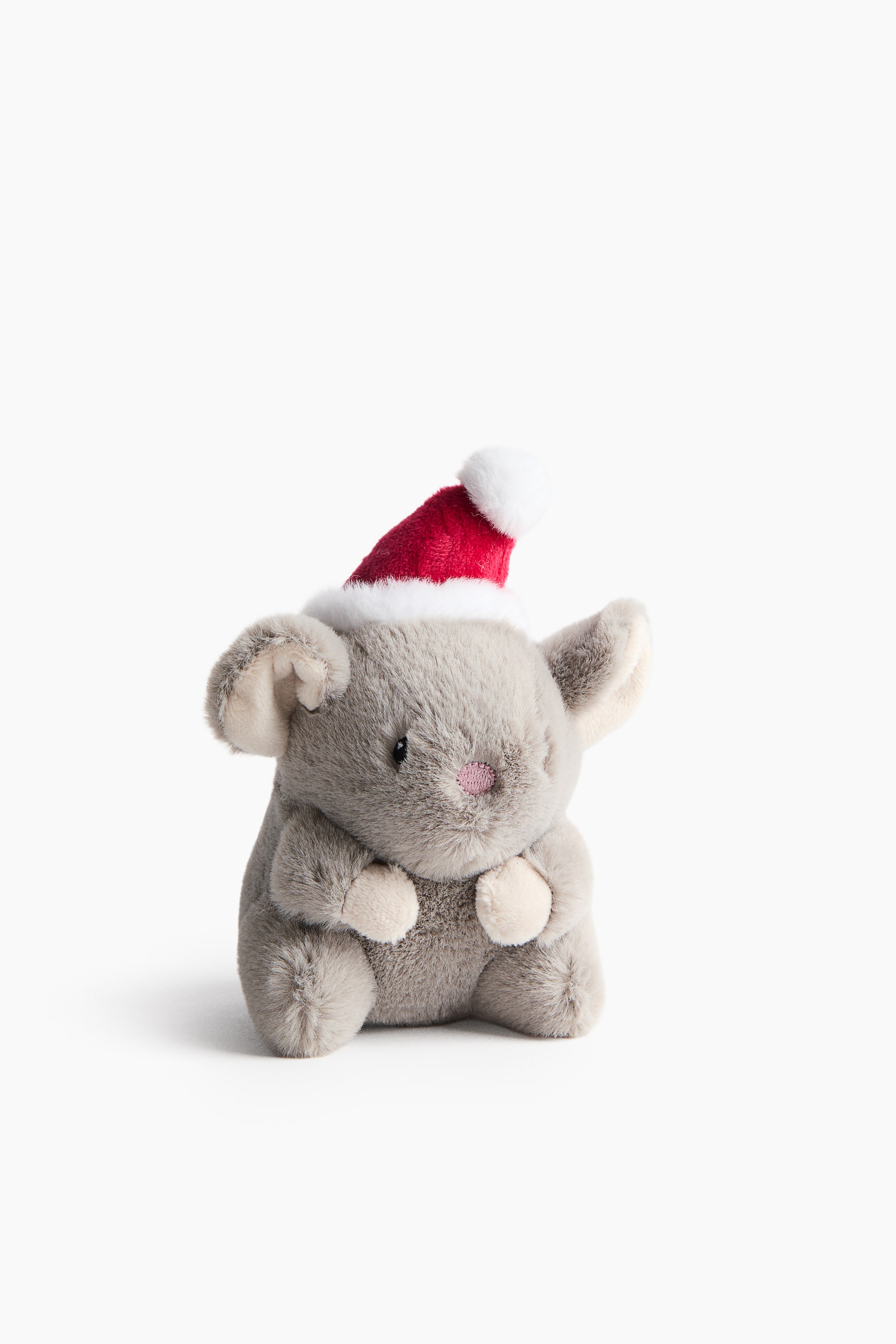 Ampliar la imagen: Un animal de peluche gris está sentado de frente. Lleva un gorro navideño rojo de Santa con borde y pompón blancos y esponjosos. El peluche muestra pequeños ojos negros, una nariz rosa bordada y el interior de las orejas y las patas en beige claro.