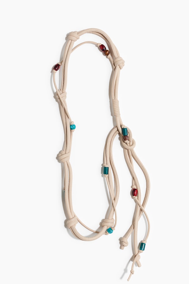A light beige cord is forming multiple loops and knots. It features various colourful beads, including spherical red, cylindrical teal, and round brown beads. - 1