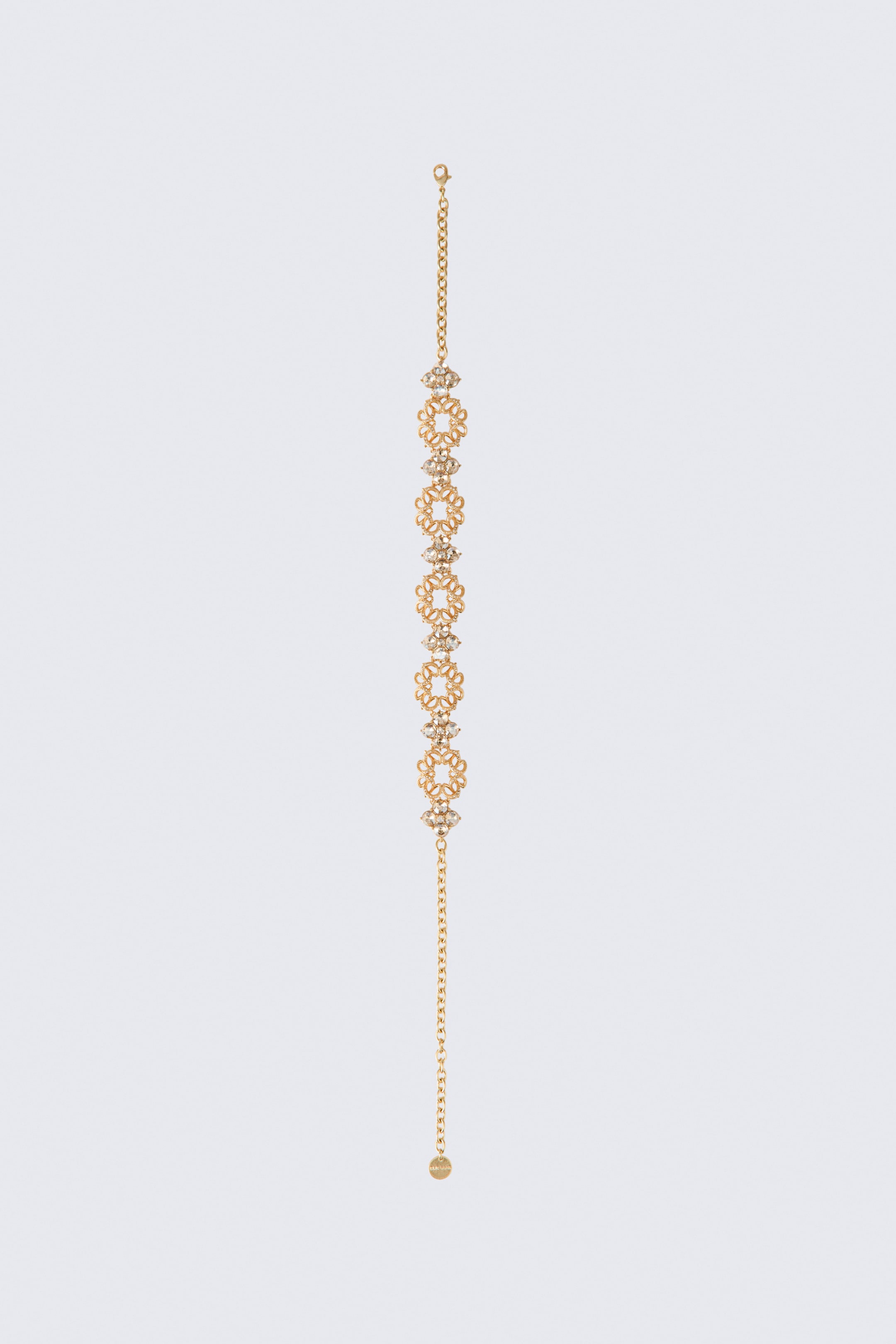 View larger image: A short rhinestone necklace is laid vertically, featuring alternating gold-tone openwork circular filigree links and floral clusters embellished with rhinestones. The necklace has a lobster clasp at one end of the chain and an adjustable extender chain with a small circular tag at the other.