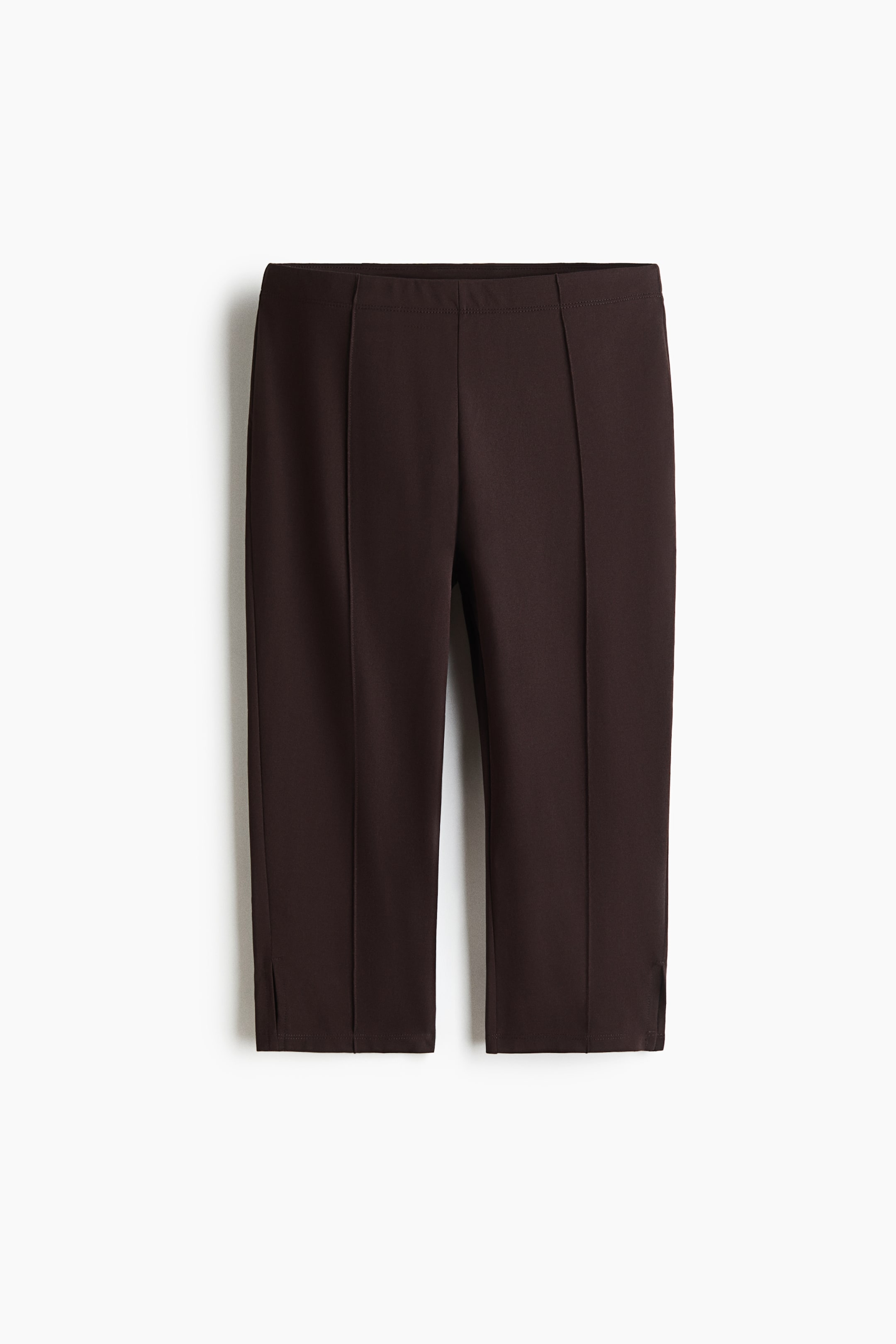 View larger image: FRONT view of dark brown cropped pants, featuring a flat waistband and vertical stitched seams running down the center front of each leg. Small side slits are detailing the hem.