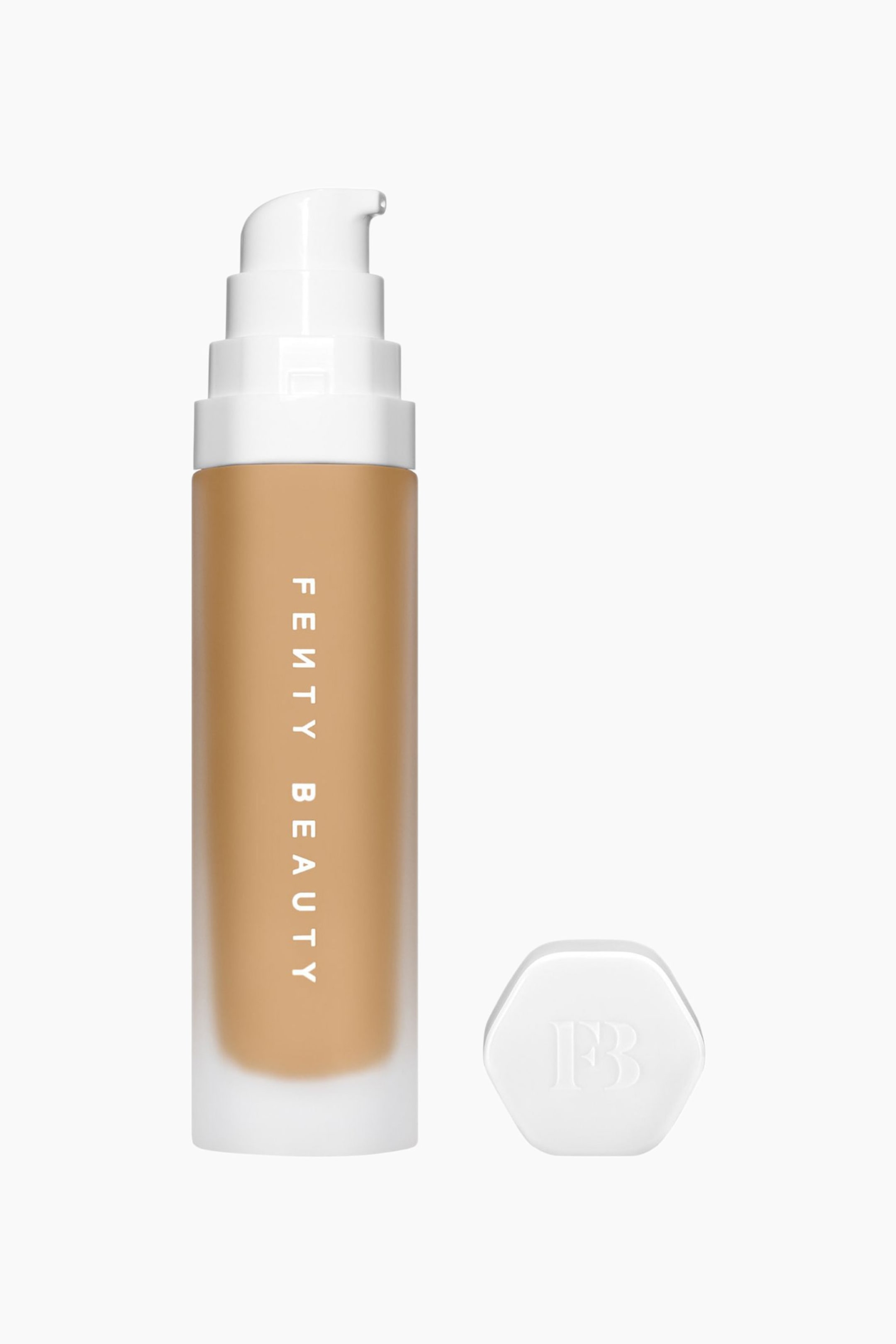 Visa större bild: Soft'lit Naturally Luminous Longwear Foundation står upprätt och visar upp en frostad cylindrisk flaska fylld med medium-tan-färgad flytande foundation och med vertikal vit ”FENTY BEAUTY”-text. En vit, skiktad pumpdispenser sitter på flaskans ovansida, medan ett separat vitt hexagonalt lock med en präglad ”FB”-logotyp ligger bredvid till höger.