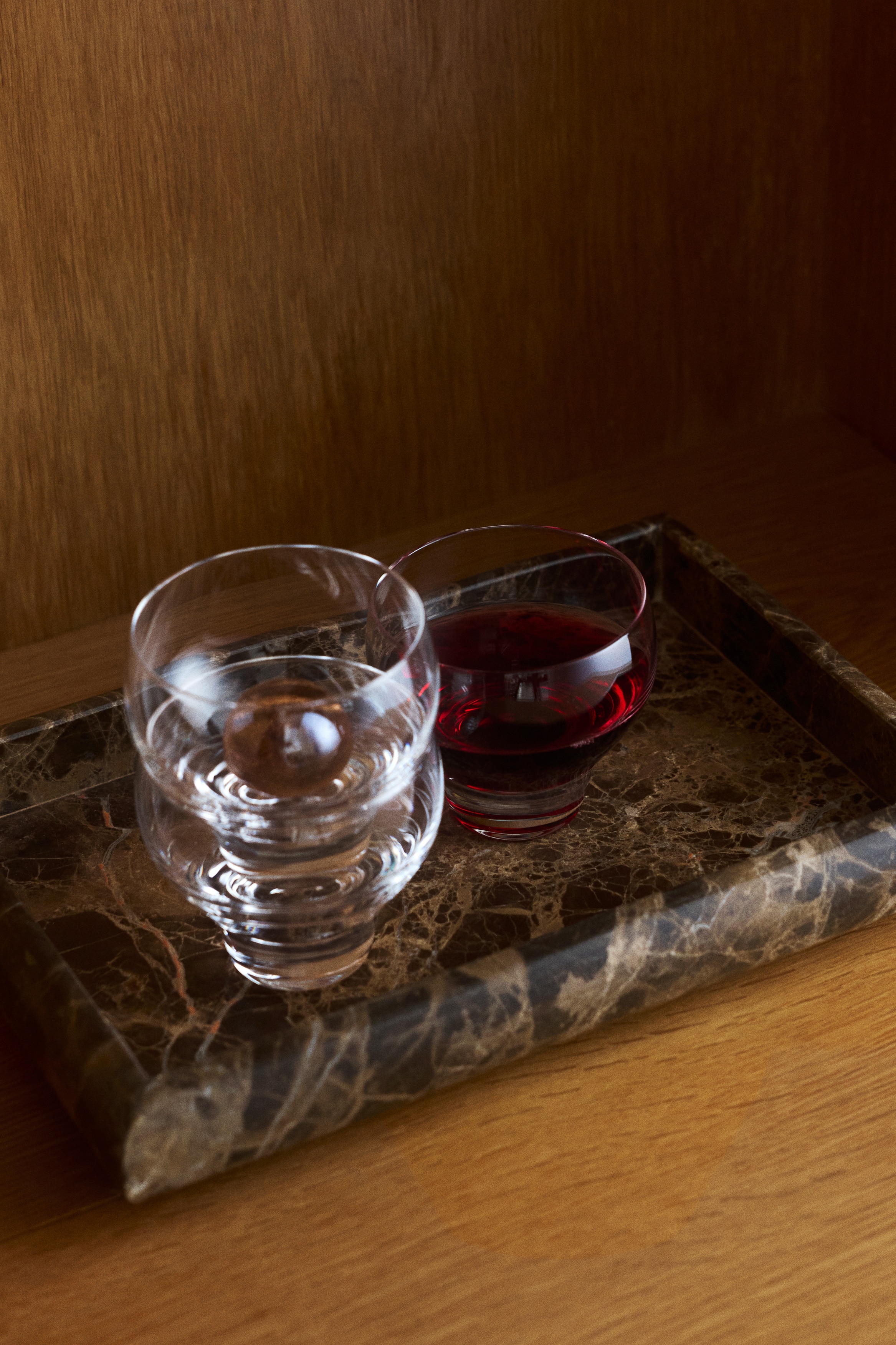 A rectangular marble tray is being displayed, featuring a dark brown colour with intricate white and lighter brown veining. It forms a shallow, rectangular basin and presents subtly rounded exterior corners.