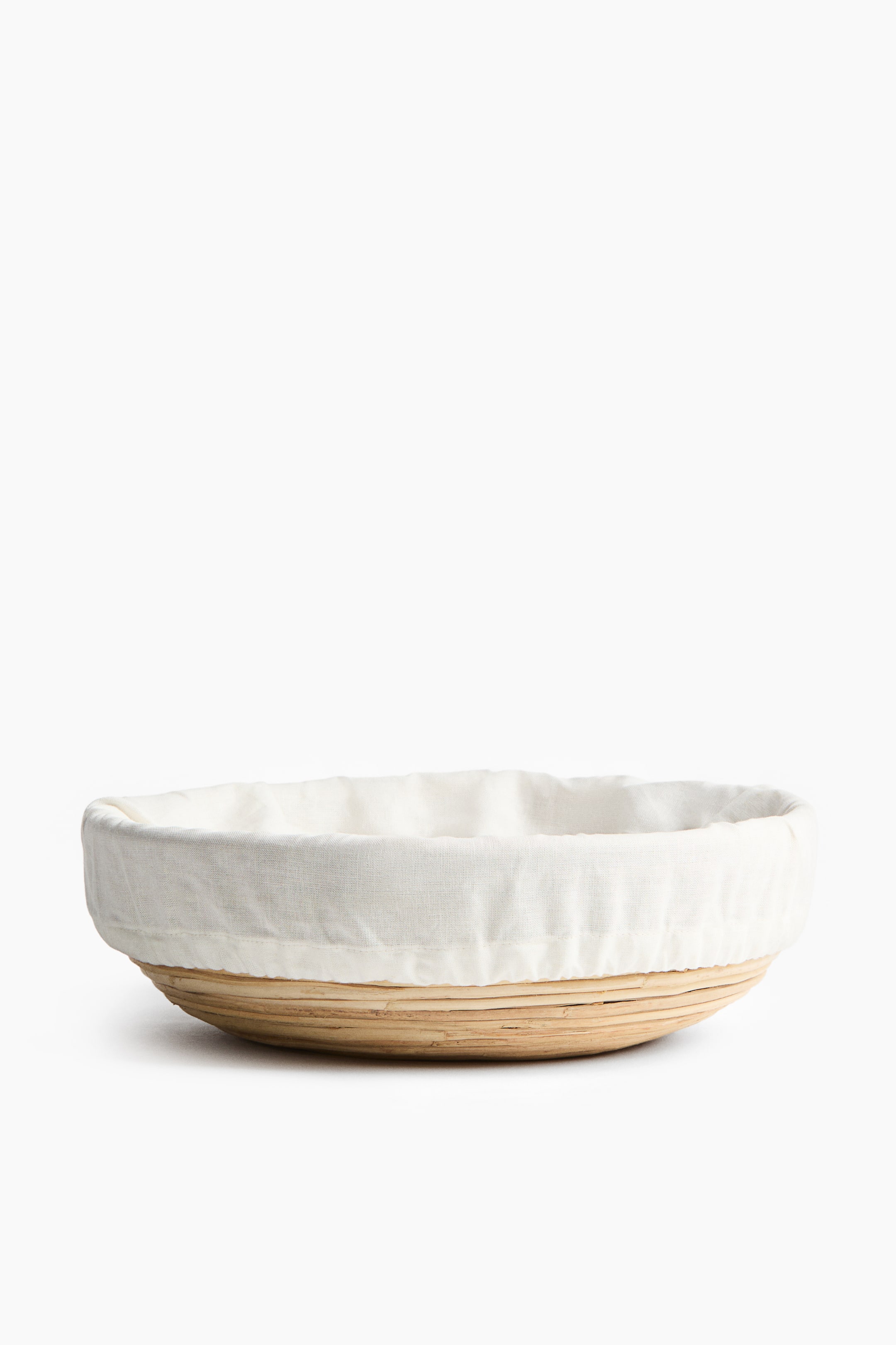 View larger image: A round proofing basket featuring light-colored woven wood strips and a white fabric liner gathered around the rim.