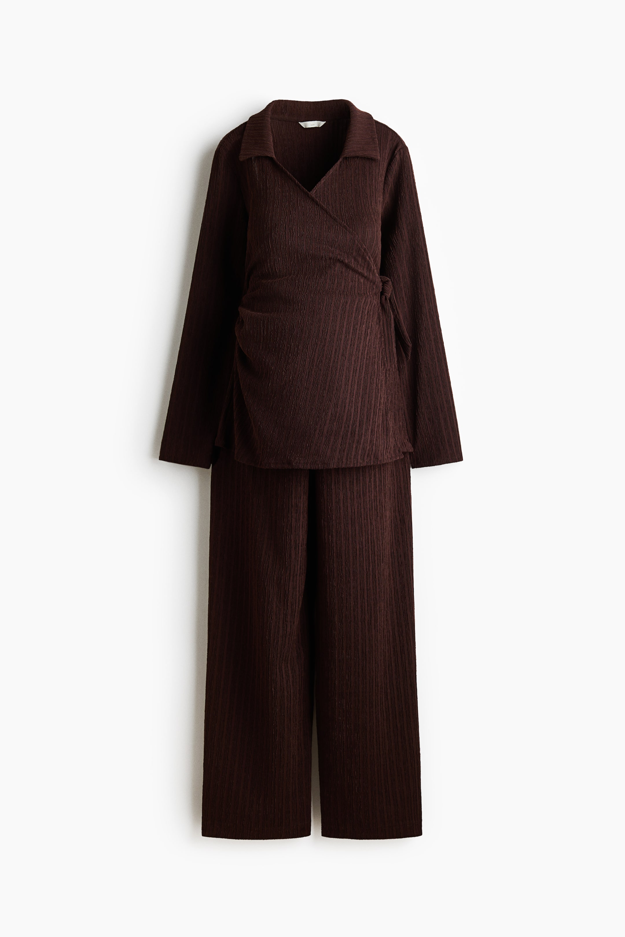 View larger image: A dark brown two-piece set features a wrap top and wide-leg pants, both with a vertical ribbed texture. The top is designed with a collared V-neckline and a visible tie-waist detail, creating gathering at the front.
