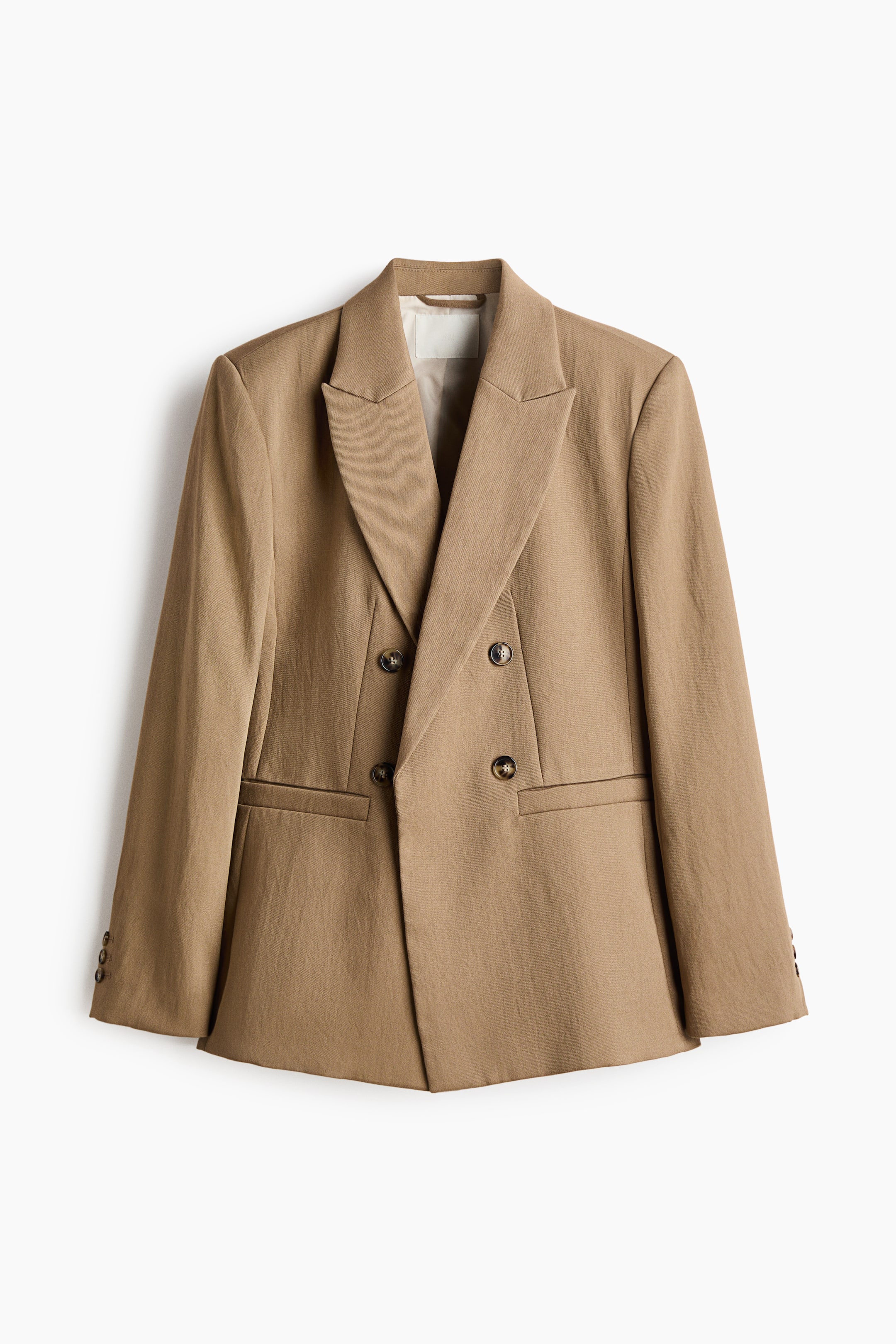 הצגת תמונה גדולה יותר: בלייזר בעל שני טורים מבד ארוג בצבע חום בהיר מציג את חזיתו, עם דשים מחודדים וכפתורים דקורטיביים בצבע חום כהה בחזית. הוא גם מציג כיסי חזית עם תפר, כריות כתף מובנות ושרוולים ארוכים עם כפתורים דקורטיביים במנשקים.