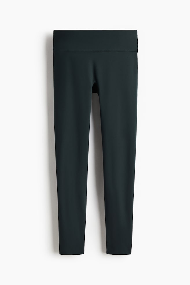 Sports leggings with SoftMove are displayed from the front, in a dark green hue. They are featuring a wide, high-rise waistband with a horizontal seam detail, and smooth, tapered legs. - 1