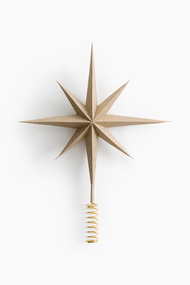 Uma estrela dourada para o topo da Ã¡rvore Ã© mostrada virada para a frente, apresentando um acabamento texturado e cintilante sobre o seu design facetado tridimensional de oito pontas. A estrela estÃ¡ ligada, na base inferior, a uma base em espiral de arame com tom dourado. - 1