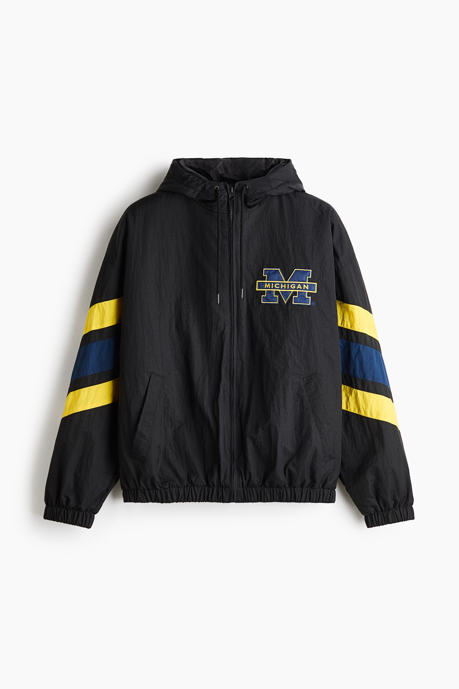 Questa giacca windbreaker nera con cappuccio è mostrata frontalmente e presenta un cappuccio con coulisse, una chiusura con zip a tutta lunghezza, tasche a filetto oblique, oltre a un orlo e polsini elasticizzati. Sul petto sinistro è visibile un logo "MICHIGAN" blu e giallo, con spesse strisce diagonali gialle e blu che avvolgono le maniche.