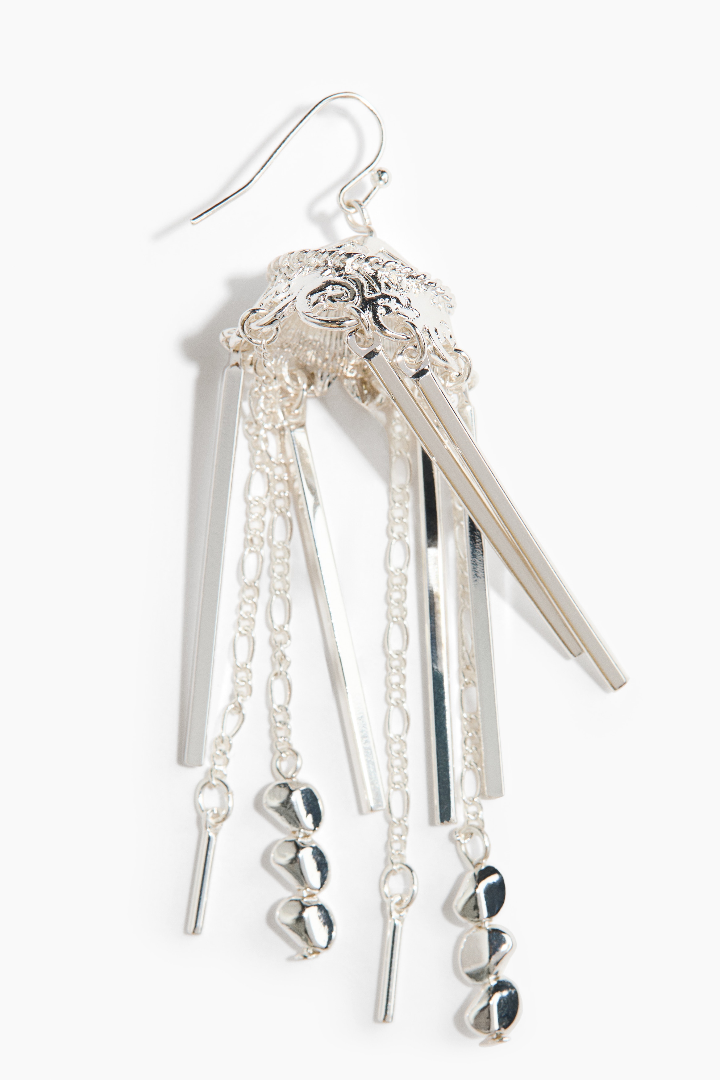 Silver-toned metal earrings featuring dangling pendants of varying lengths and designs are being worn by the model. The earrings are styled with a white ruffled blouse and multiple rings featuring pearl embellishments.