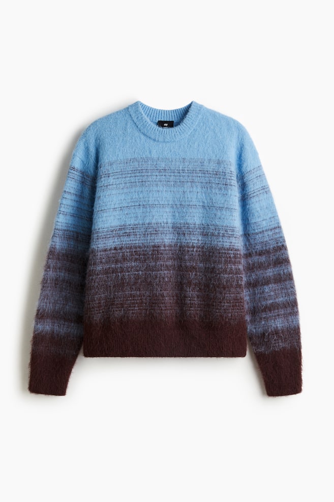 Ein flauschiger Pullover zeigt eine Vorderansicht mit einem Ombré-Muster, das von Hellblau oben zu Dunkelbraun unten übergeht. Die hellblauen Abschnitte zeigen dünne, horizontale dunkle Streifen. Er ist mit einem gerippten Rundhalsausschnitt, langen Ärmeln und einem gerippten Saum und Bündchen gestaltet. - 1