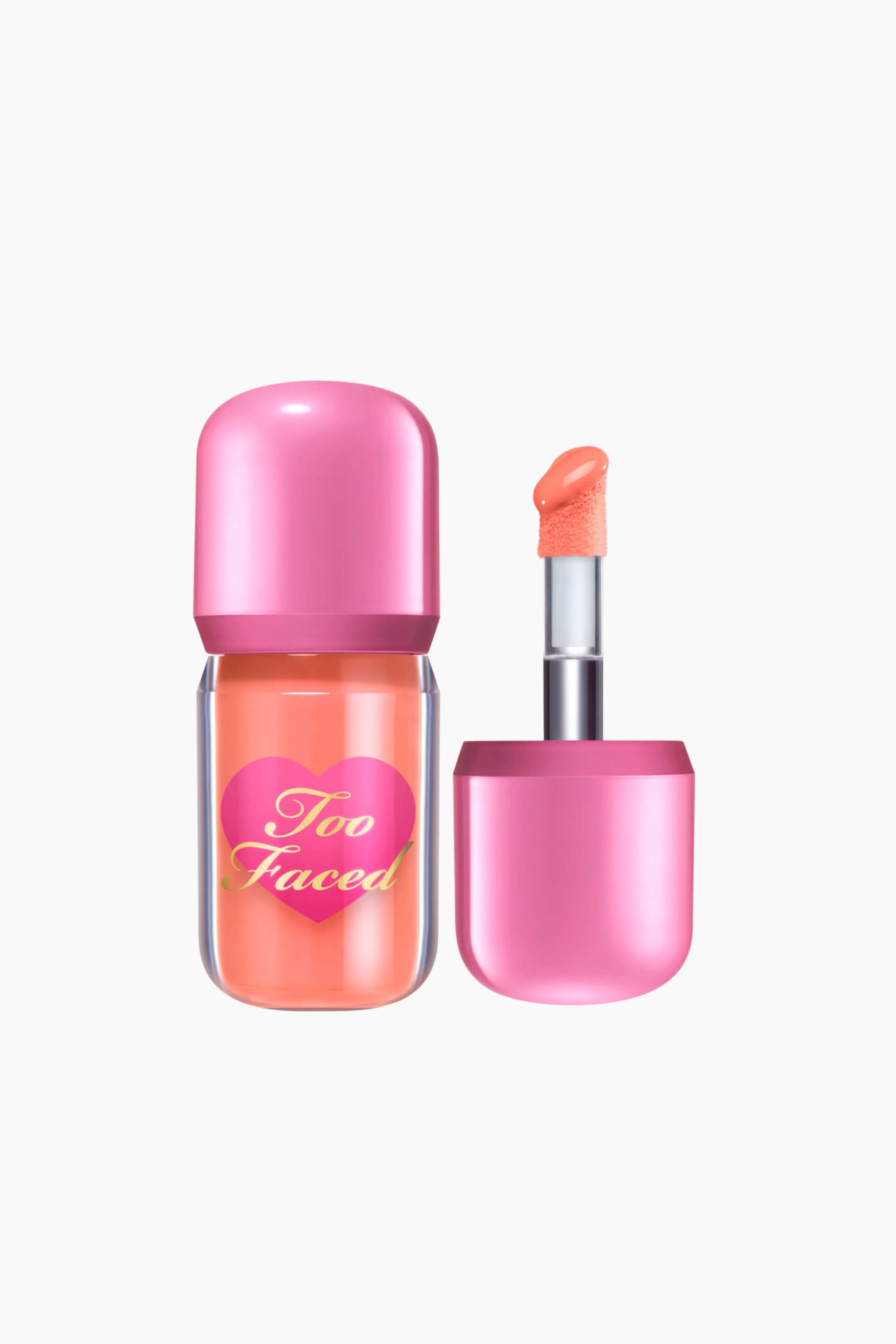 Vis større bilde: En klar, rektangulær kosmetikkflaske med avrundede kanter viser en oransje-ferskenfarget væske og en rosa hjerteformet "Too Faced"-etikett, mens den avrundede, skinnende rosa hetten er løsnet, og avslører en applikator med hjorte-fot form som er dekket med det samme oransje-fersken produktet.