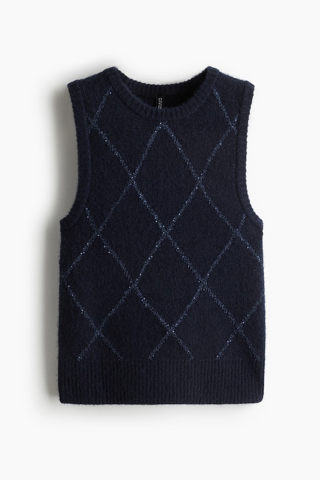 Ein dunkelblauer Pullover mit V-Ausschnitt wird von vorne gezeigt, mit einem runden Ausschnitt und einem gerippten unteren Saum. Ein argyle-ähnliches Rautenmuster bedeckt den Körper, wobei die Linien sichtbar schimmern. - 1