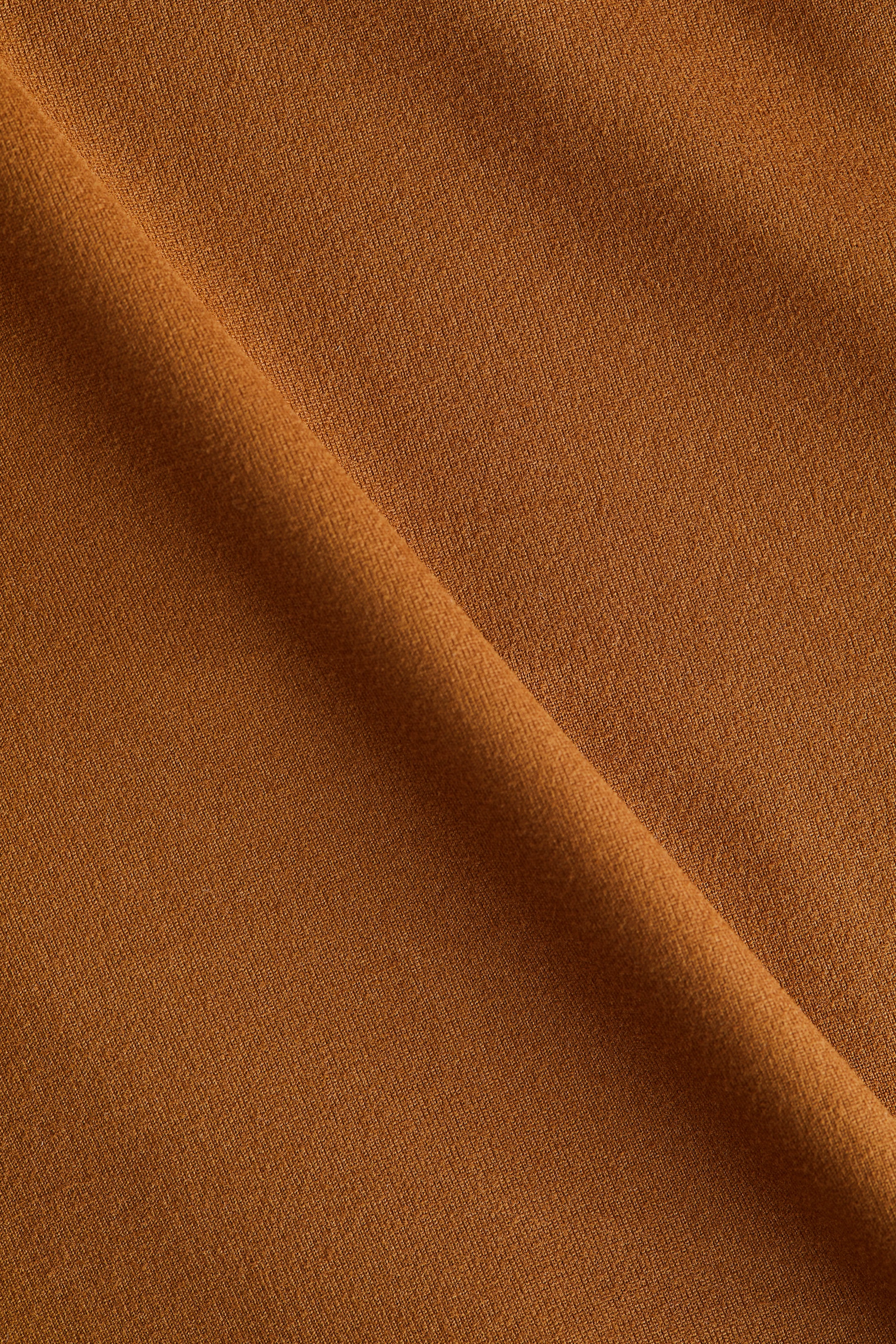 View larger image: A solid rust-colored fabric is showing a subtle diagonal texture, with a soft diagonal fold creating depth.