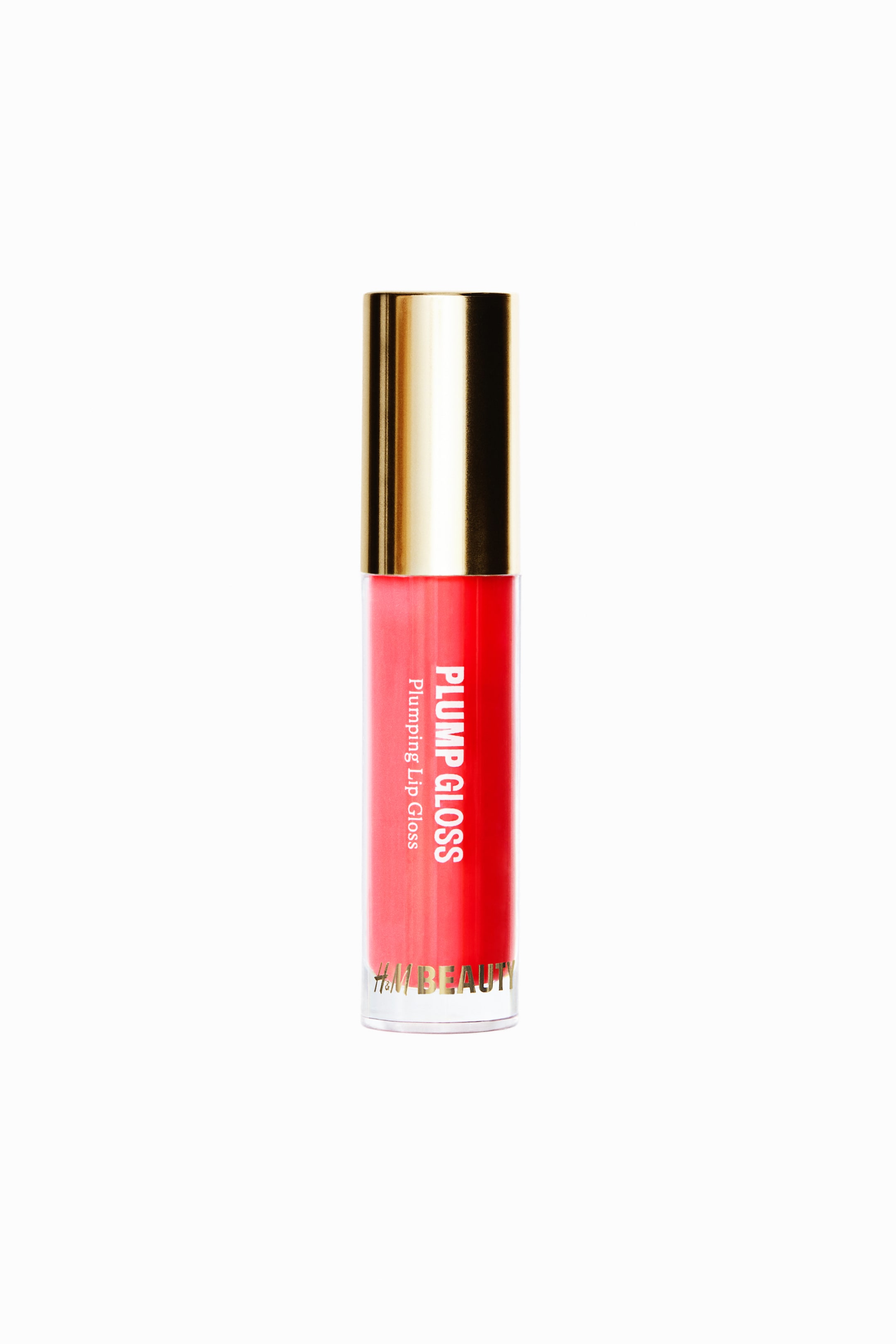 View larger image: A cylindrical tube of lip gloss is standing upright, showing a vibrant coral-red gloss inside a clear container topped with a metallic gold cap. The front of the tube is displaying vertical white text that reads "PLUMP GLOSS" and "Plumping Lip Gloss," with gold lettering at the bottom reading "H&M BEAUTY."