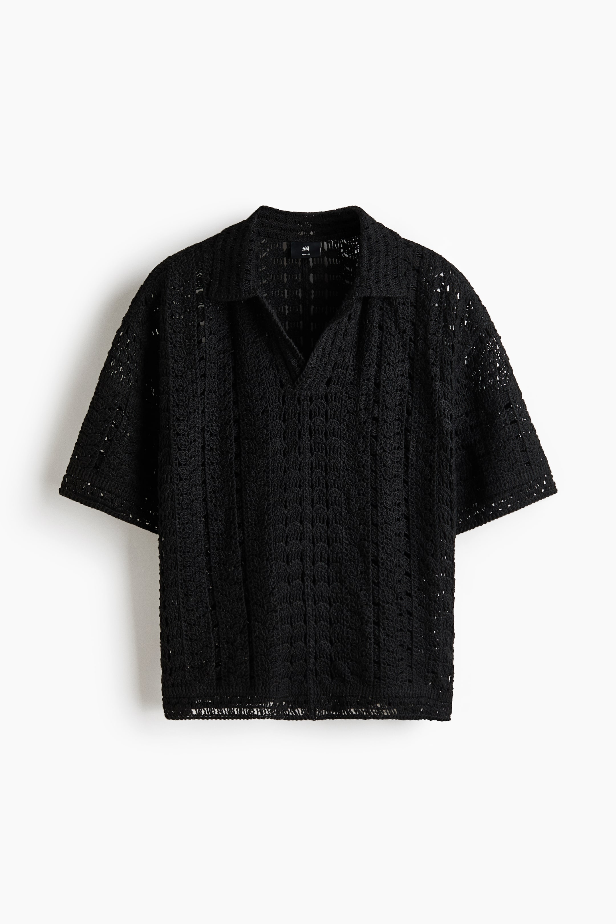 View larger image: Black crochet polo shirt is facing forward, featuring a spread collar and a V-neckline. It showcases short sleeves and an intricate, open crochet knit pattern throughout.