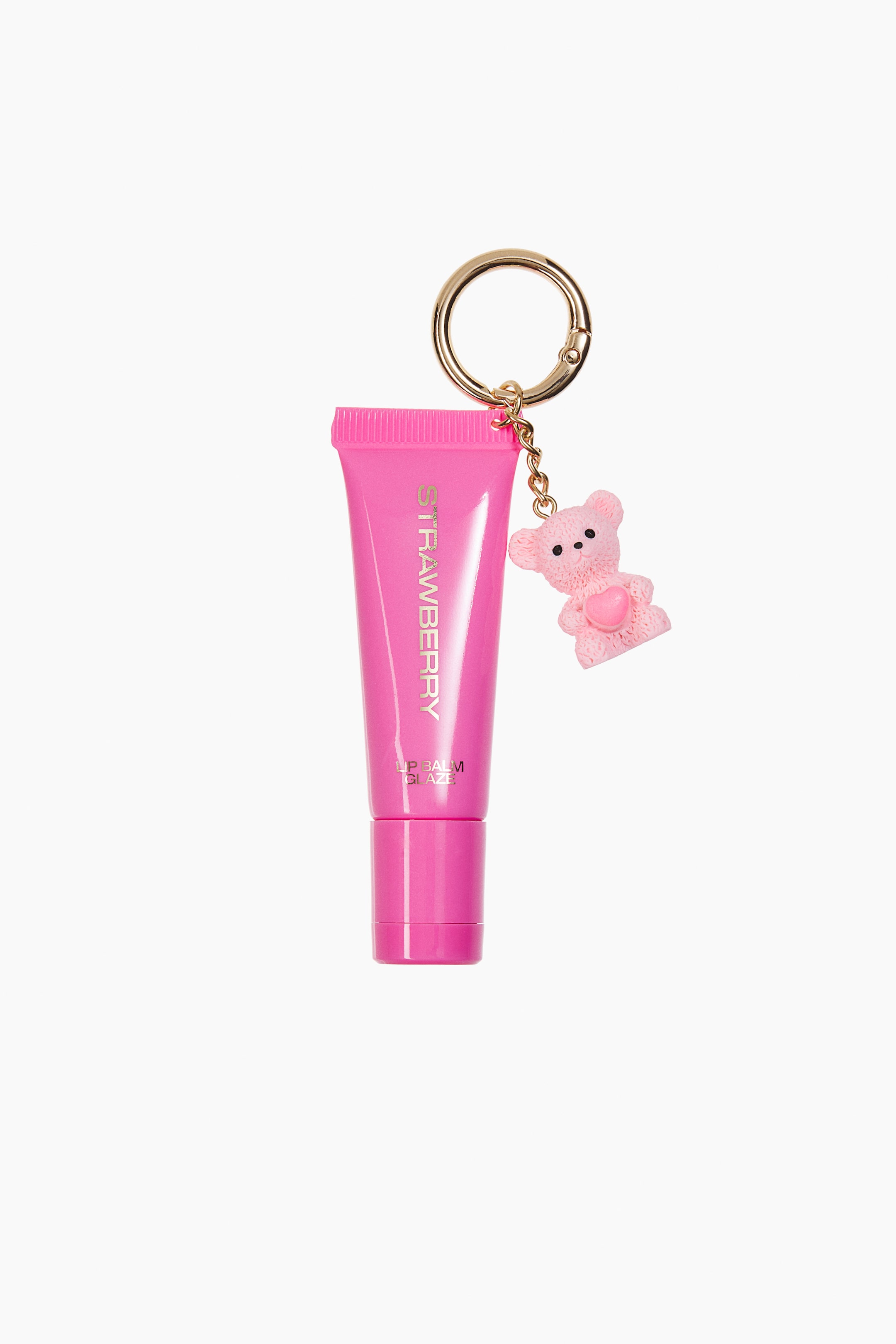 View larger image: A bright pink squeeze-tube lip balm is shown from the front, featuring metallic lettering that reads "STRAWBERRY" and "LIP BALM GLAZE". A gold-toned circular carabiner clasp is attached to the crimped top of the tube, holding a dangling, textured pink teddy bear charm.