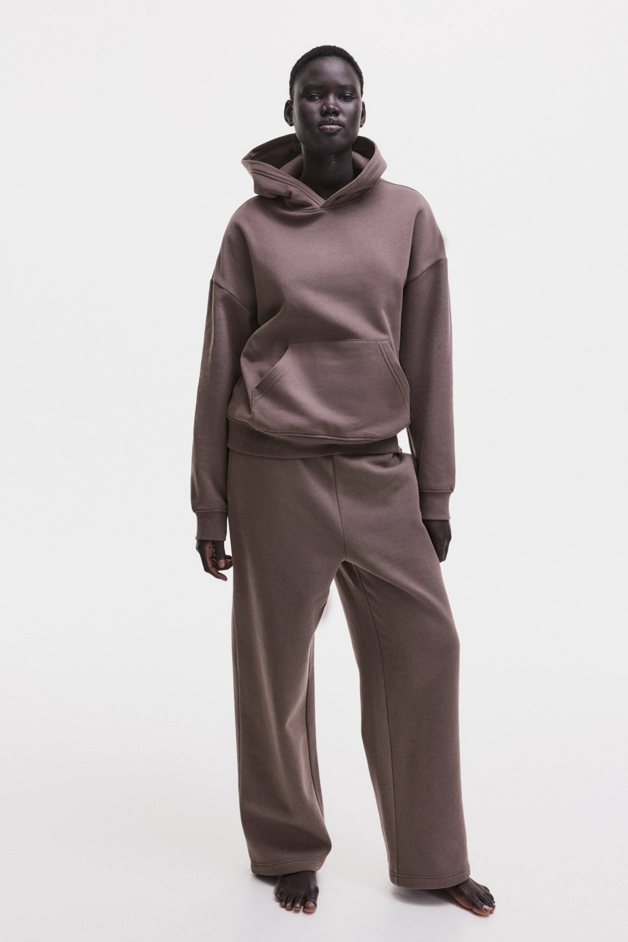 View larger image: A dark brown matching loungewear set features an oversized hoodie with a hood, a front kangaroo pocket, ribbed cuffs, and a ribbed hem. The matching wide-leg sweatpants offer a relaxed fit and clean hems.