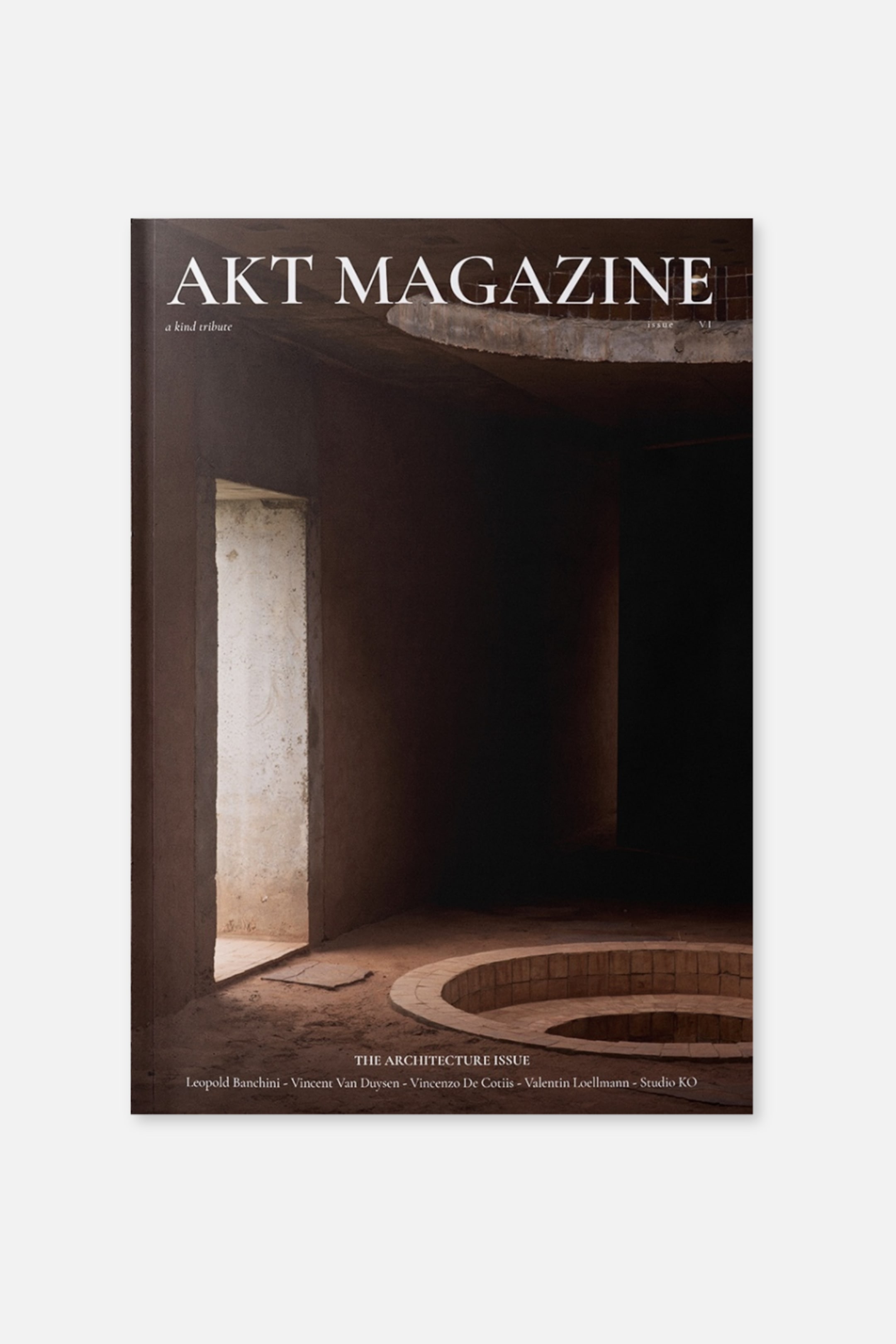 Agrandir l'image: La couverture en façade du numéro « The Architecture Issue » d’Akt Magazine présente une photographie d’un intérieur minimaliste en béton aux tons terreux, avec une porte lumineuse et une structure circulaire en briques en retrait. En haut, le titre « AKT MAGAZINE » apparaît dans une police serif blanche, tandis qu’en bas figure « THE ARCHITECTURE ISSUE », accompagné des noms des designers collaborateurs.