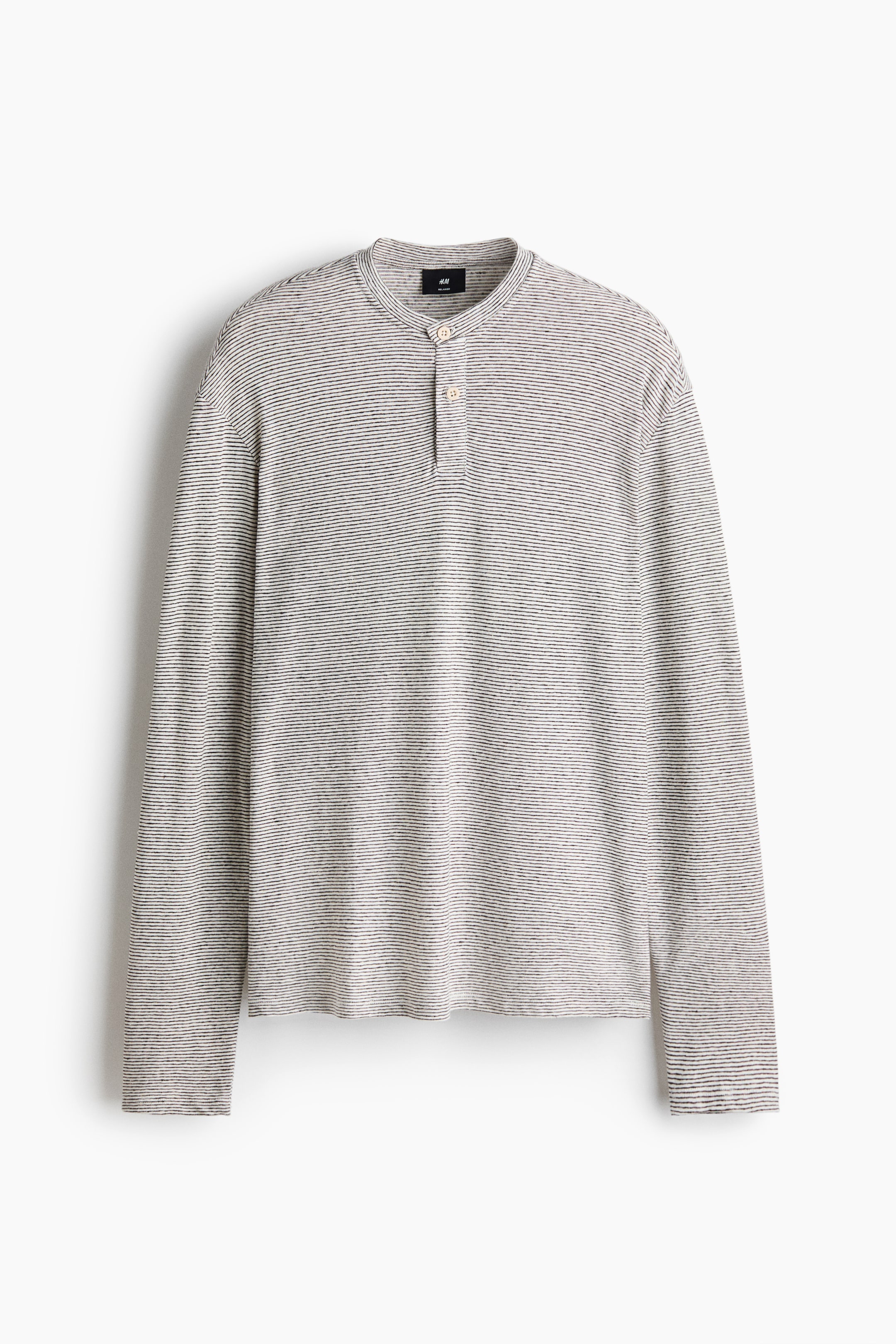 Grotere afbeelding bekijken: Het Henley-shirt met lange mouwen ligt plat en naar voren gericht, en toont een getextureerde lichtgrijze stof met dunne horizontale zwarte strepen. Het is voorzien van een bandkraag en een sluiting met twee knopen met lichtgekleurde knopen.