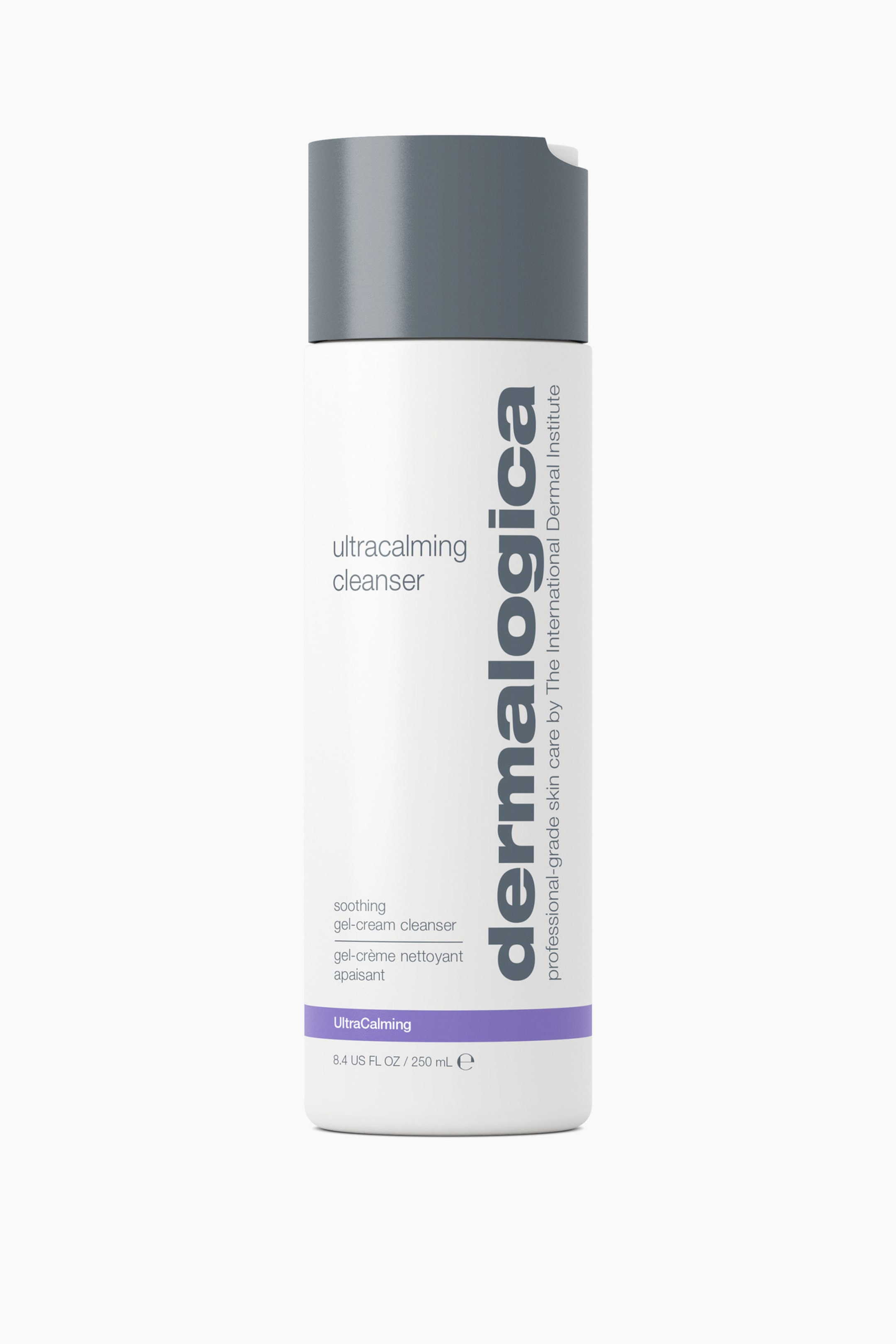 Visa större bild: Dermalogica Ultracalming Cleanser står upprätt i en framifrån-vy och framträder som en hög, cylindrisk vit flaska med en mattgrå kork. Flaskan har vertikal "dermalogica"-branding i mörkgrått på högra sidan och ett enfärgat lila horisontellt band som löper runt den nedre delen ovanför volymuppgifterna.