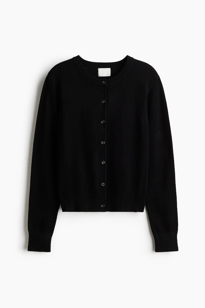A black fine-knit cardigan is facing the front, featuring a ribbed crew neck, a vertical row of seven dark buttons down the center, and ribbed detailing on the cuffs and hem. - 1