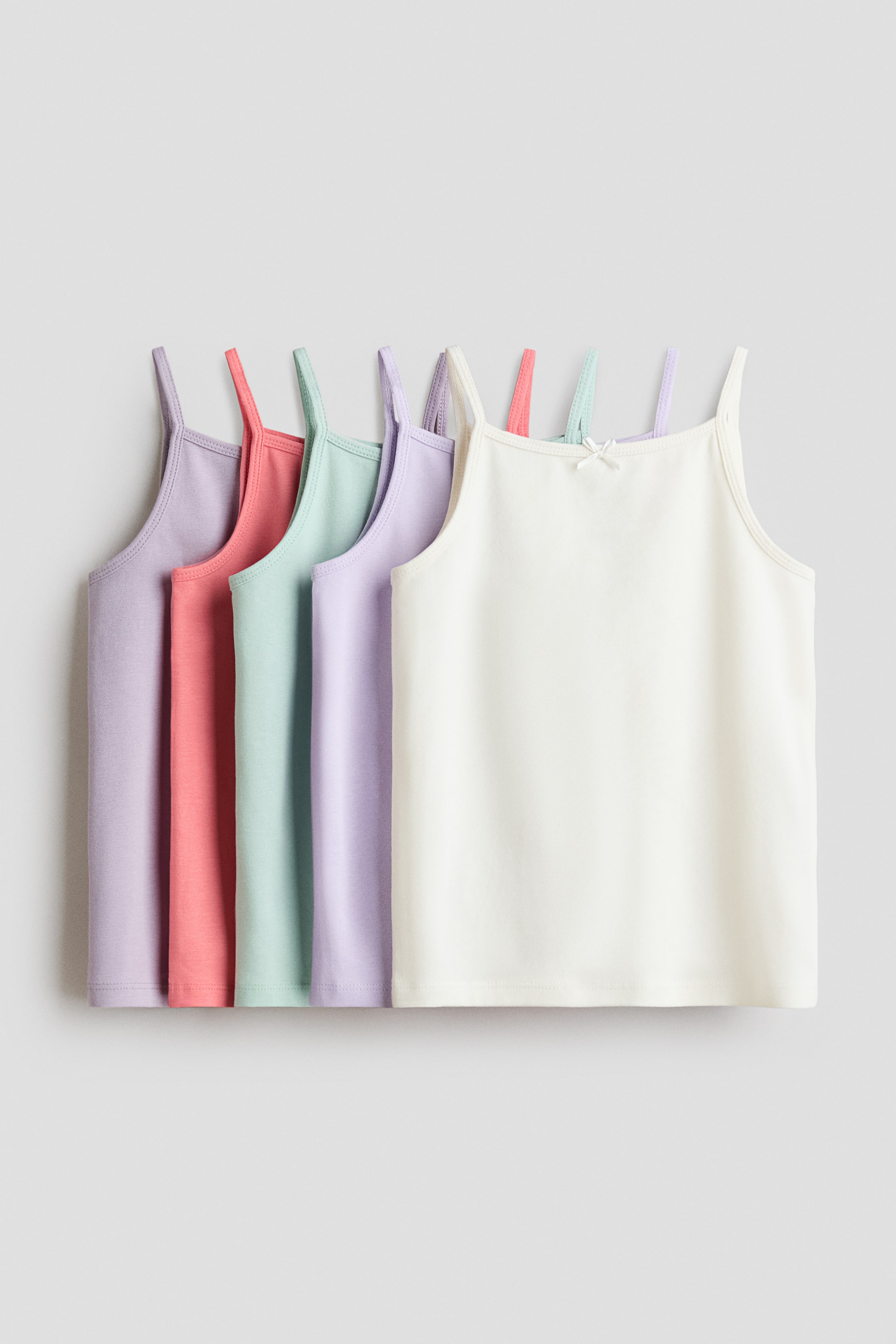 Agrandir l'image: Cinq débardeurs en jersey de coton sont présentés de face, chacun doté de fines bretelles, de finitions picot en haut et d'un nœud décoratif en satin à l'avant, apparaissant dans des tons pastel de violet clair, corail, vert clair et blanc cassé.
