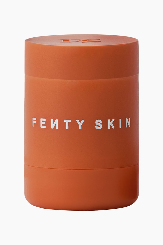 En cylindrisk lÃ¦beplejecontainer i terrakottafarve stÃ¥r oprejst og har hvid blokskrift med "FE?TY SKIN" pÃ¥ tvÃ¦rs af midten. Produktet med mat finish har et opdelt design med et prÃ¦get "FS"-logo pÃ¥ den flade topflade. - 1