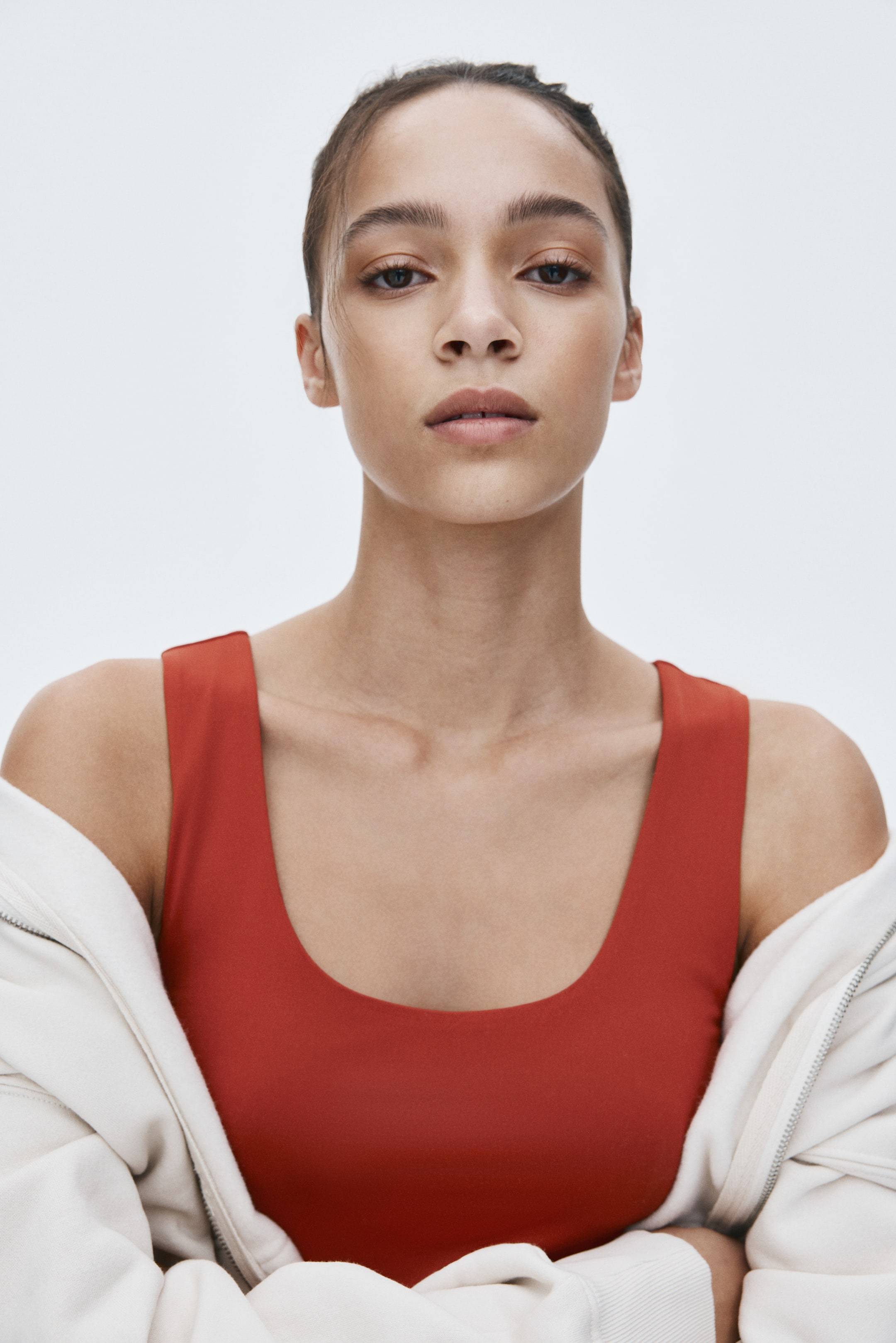 View larger image: A light cream zippered jacket is draping over the shoulders, partially revealing the top's front.