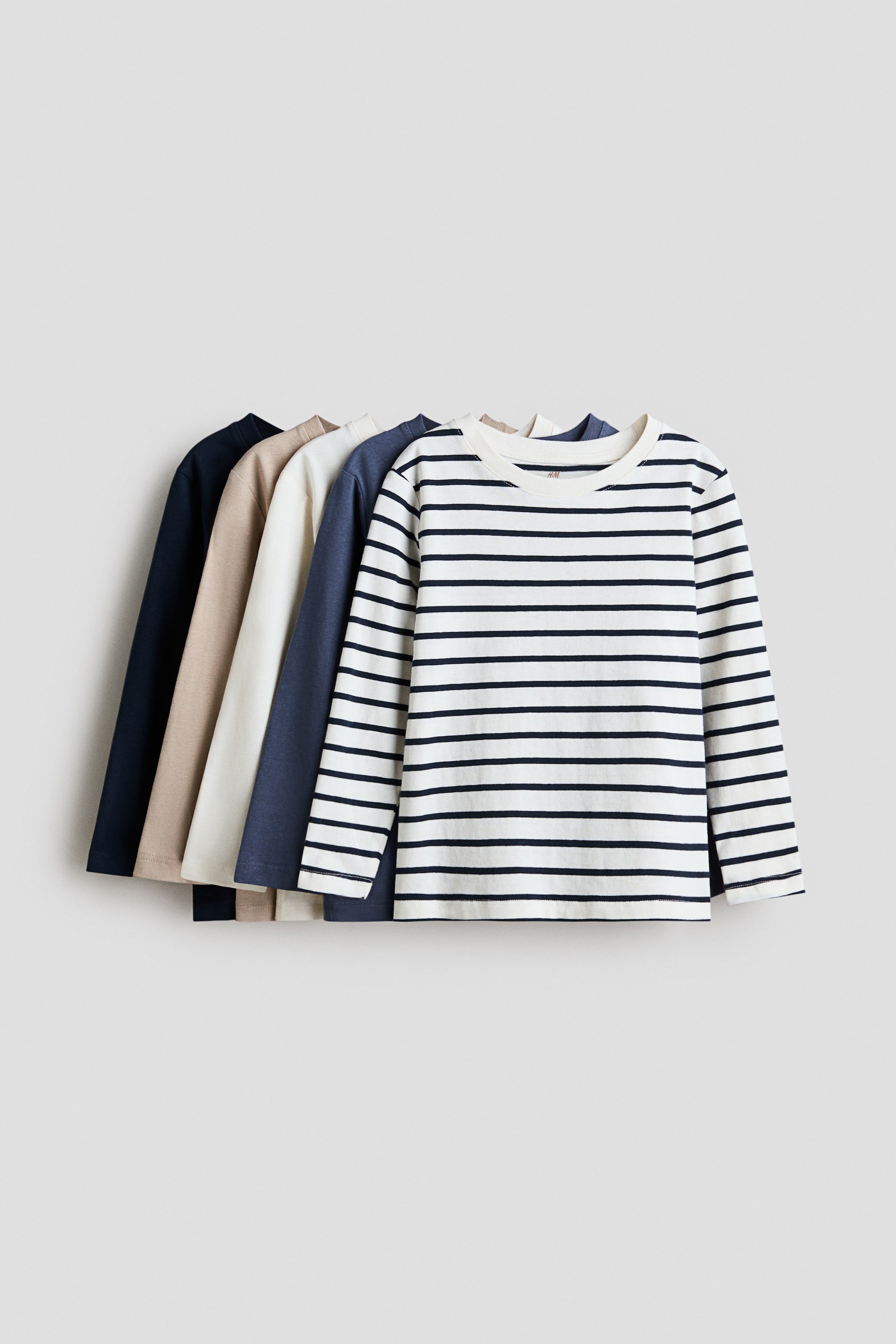 View larger image: The front shirt is white with thin black horizontal stripes, while the four shirts behind it are solid dark blue, off-white, beige, and dark navy, respectively.
