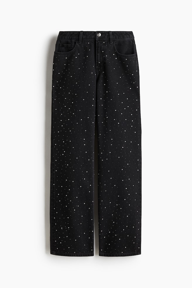 Black, straight-leg jeans are presented from the FRONT, featuring scattered silver studs across the entire fabric. They are showing a waistband with belt loops, a button closure, and two front pockets with a coin pocket on the right side. - 1