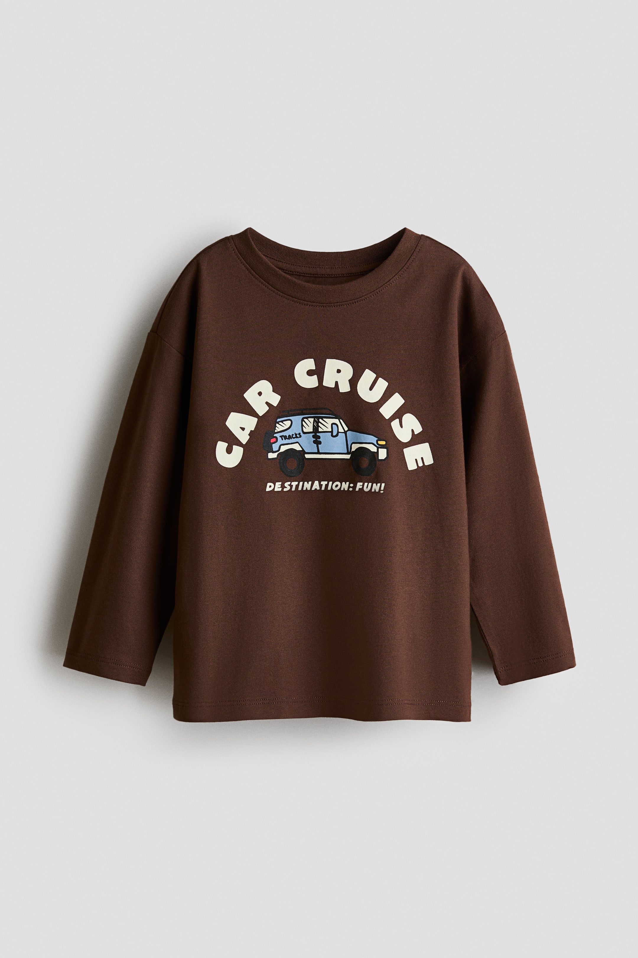 View larger image: The long-sleeved t-shirt showcases a brown hue and a round neckline. The front displays a graphic print with the words 'CAR CRUISE' in white, arching above a light blue cartoon SUV. Below the SUV, the text 'DESTINATION: FUN!' is visible in white.