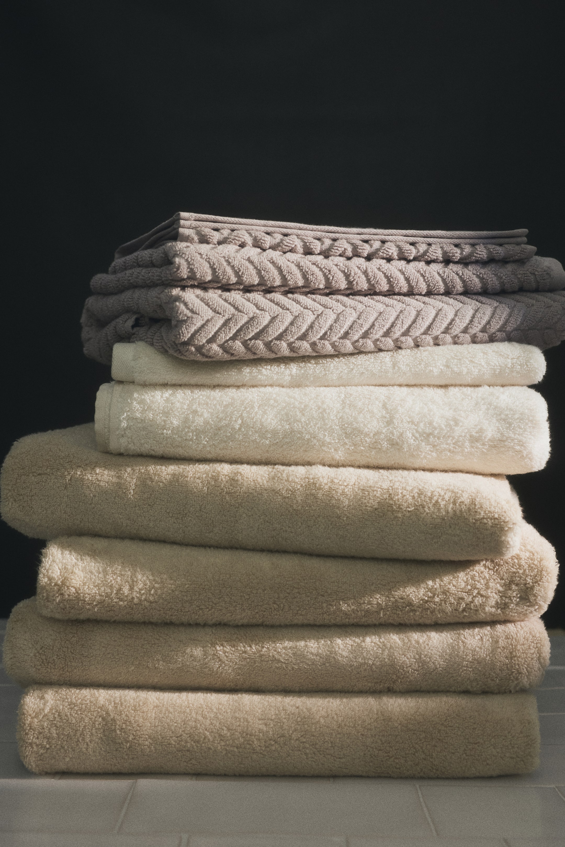 View larger image: Two light brown guest towels are folded and stacked, prominently displaying a textured, cable-knit-inspired design on their terry surface.