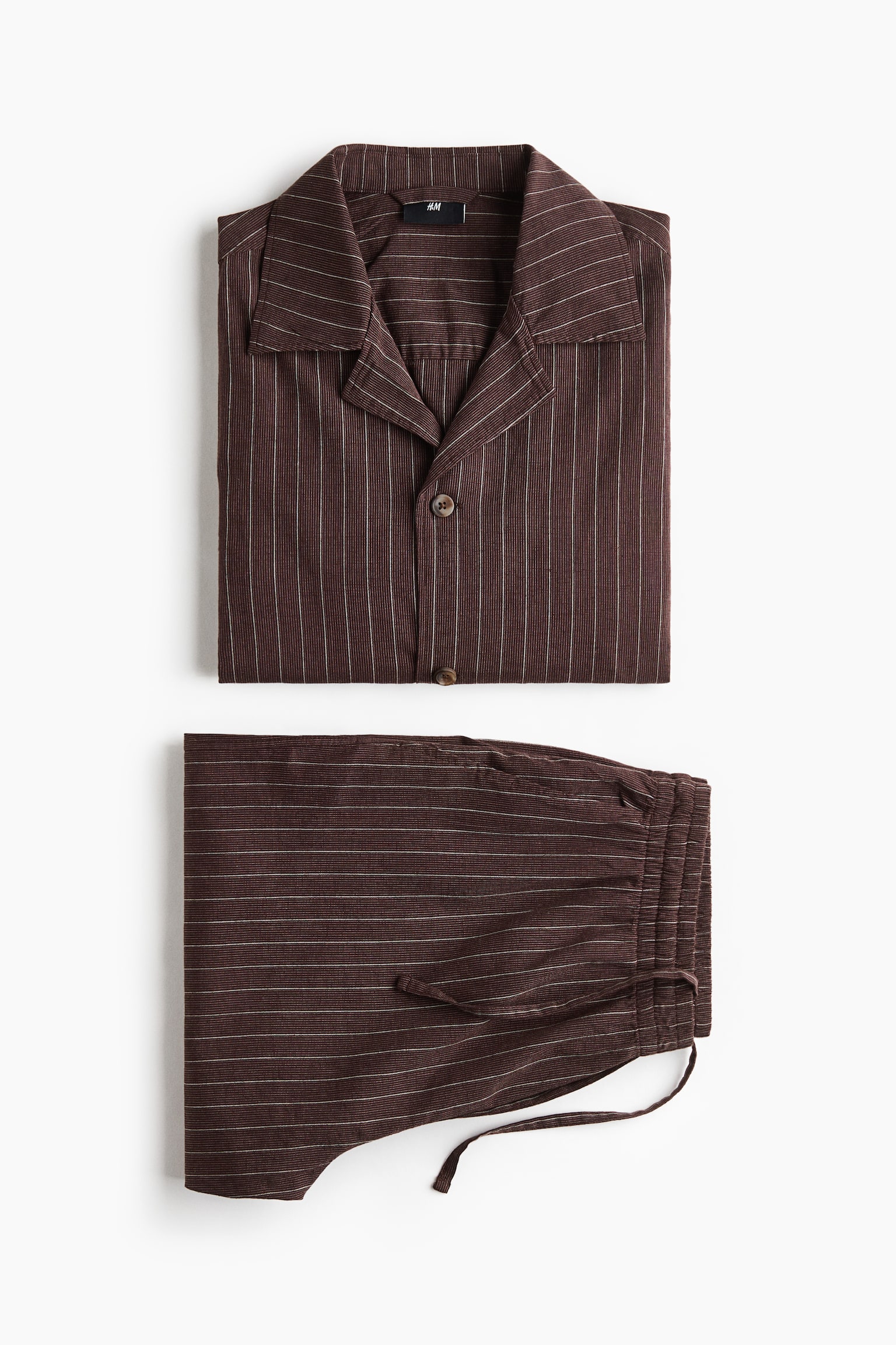 A dark brown shirt and shorts set, made from an airy cotton and linen weave, is presenting from the front. The shirt is featuring thin white vertical stripes, a resort collar, buttons down the front, and an open chest pocket. The shorts are showing thin white horizontal stripes, a covered elastic waistband with a drawstring, and a stitched fake fly. - 1