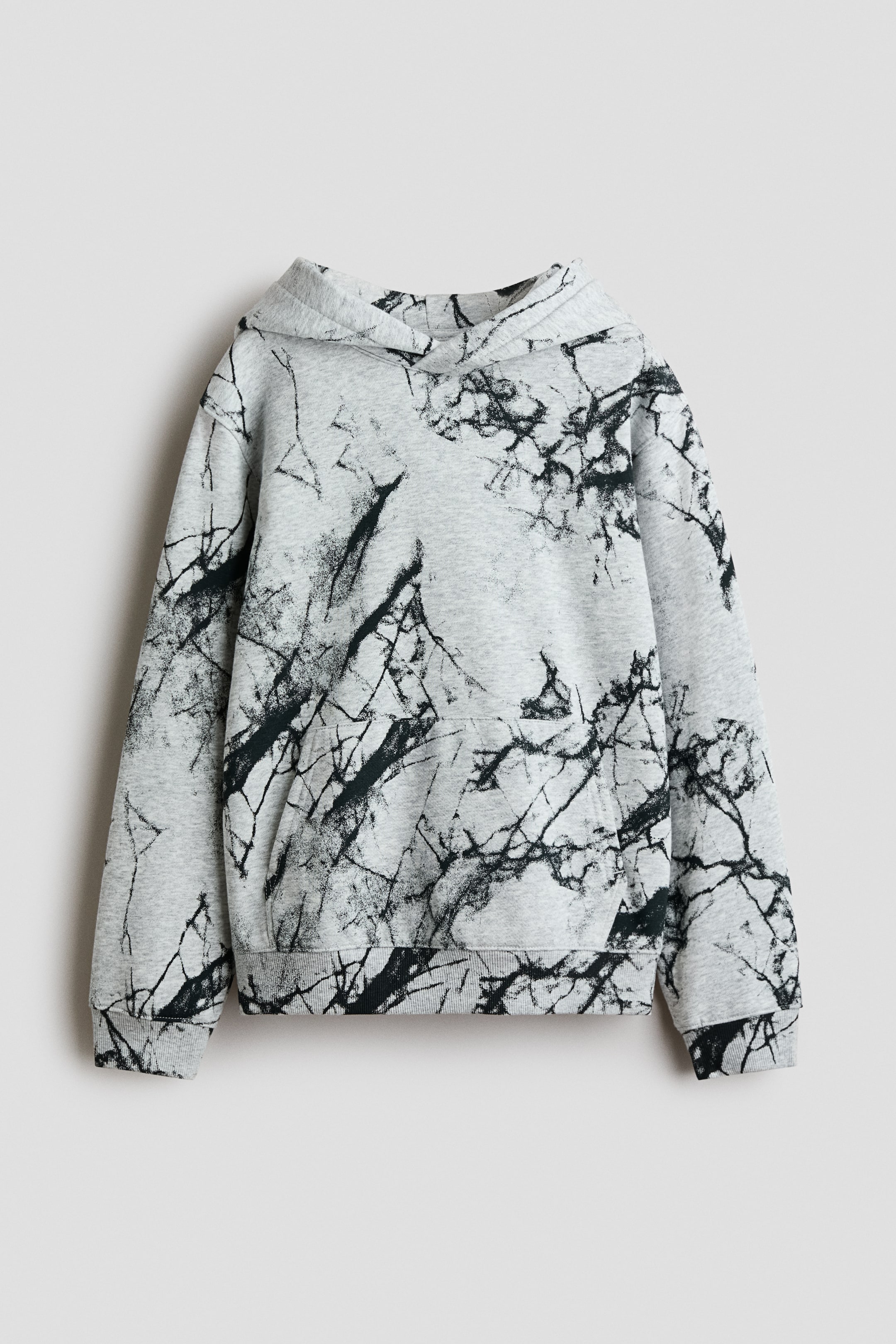 Voir une image plus grande: Un hoodie est présenté de face, mettant en valeur un tissu molletonné imprimé gris pâle avec un motif abstrait noir. Il est doté d’une capuche doublée de jersey avec un devant croisé, d’épaules tombantes, de manches longues, d’une poche kangourou et de bord-côtes aux poignets et à l’ourlet.