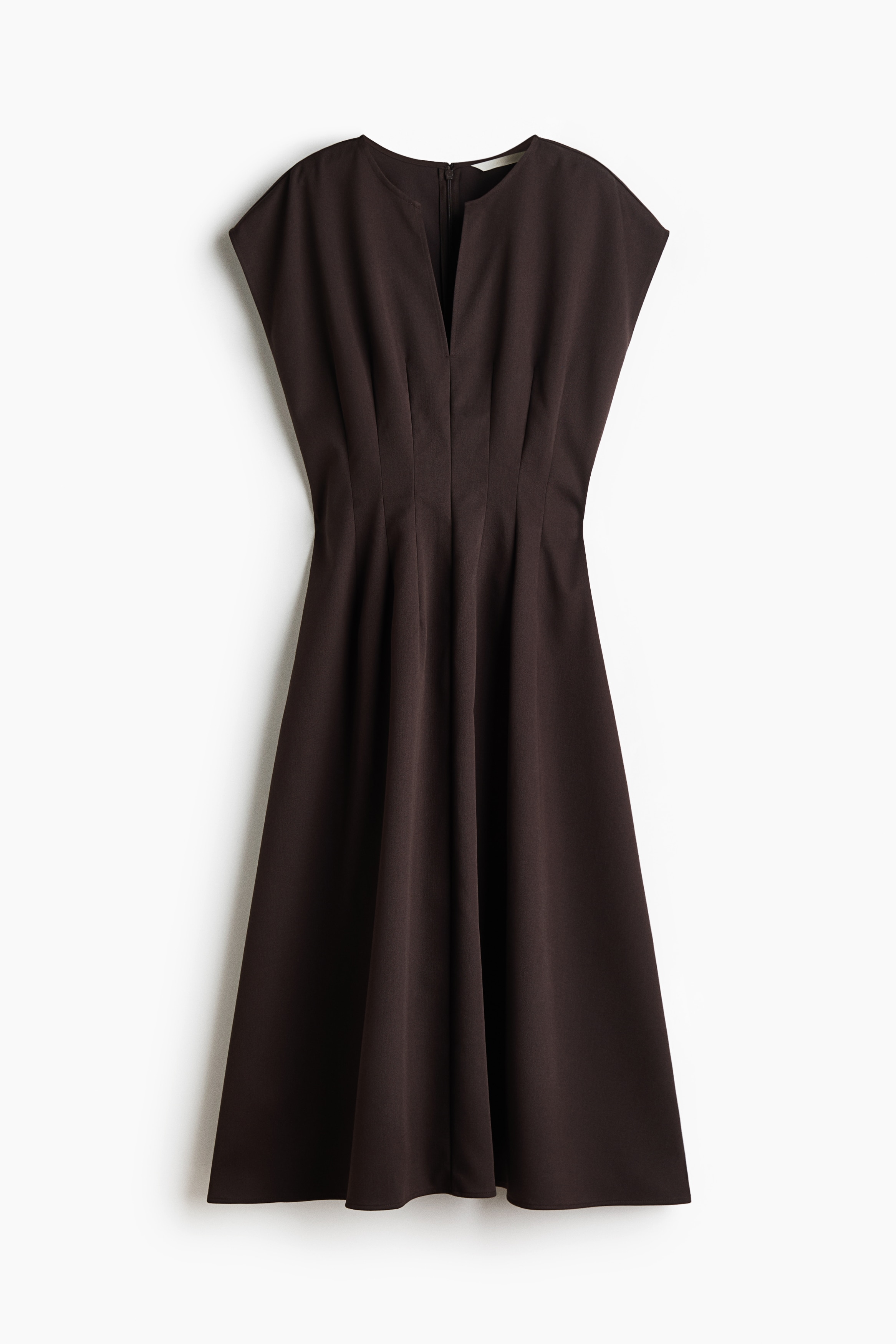 La modelo lleva un vestido color cafÃ© oscuro, a la pantorrilla, con escote en V, mangas cortas y falda evasÃ©. Sobre un hombro del vestido lleva un trench coat a cuadros en tonos cafÃ© y beige, combinado con botas negras de cuero con tacÃ³n alto.