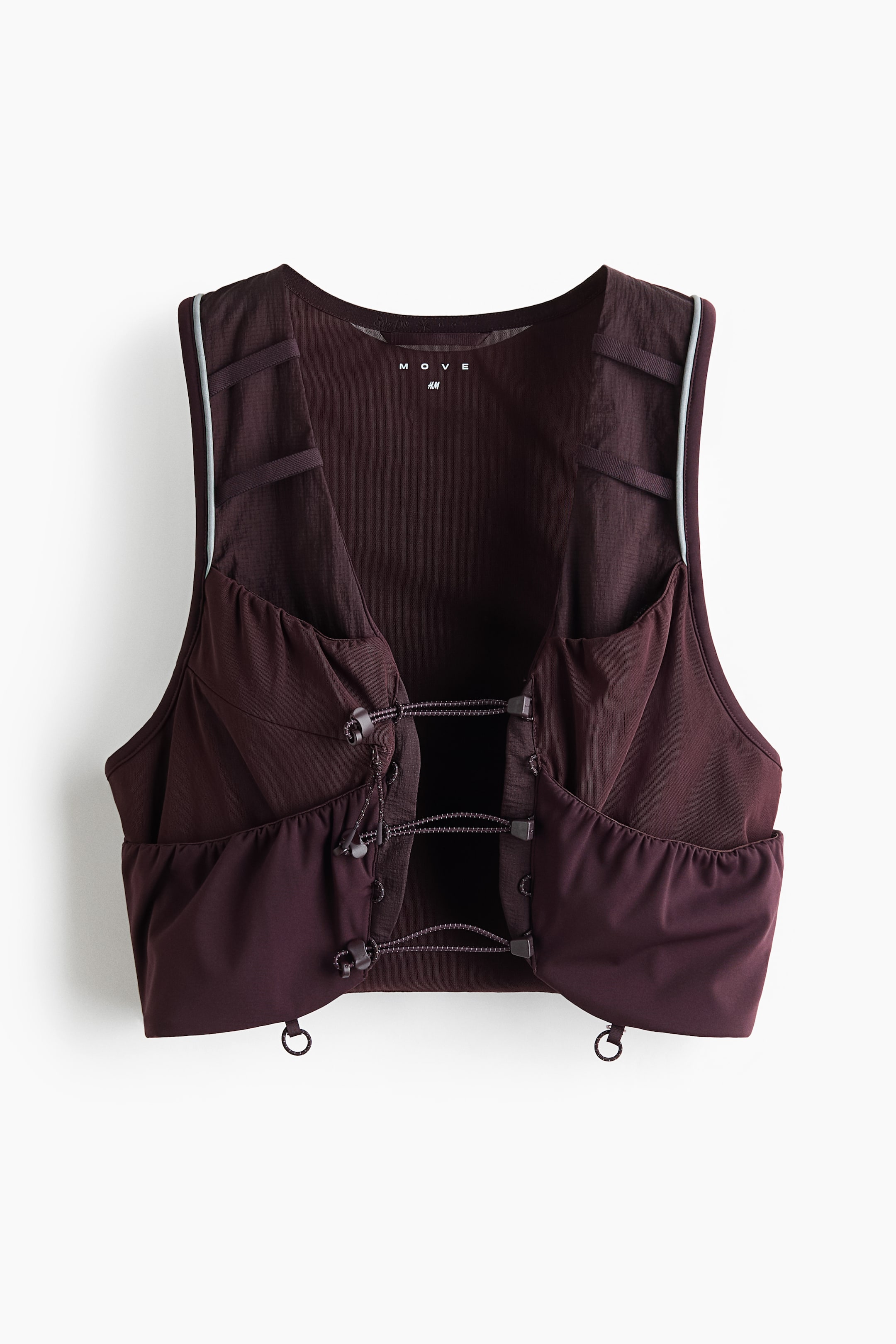 View larger image: A cropped dark brown vest is presenting its front, featuring mesh upper panels with horizontal straps and light blue piping along the shoulder seams. The front closure is utilizing three horizontal elastic cords with black toggle stoppers, and the lower front is featuring gathered fabric with small D-rings visible at each side of the hem.