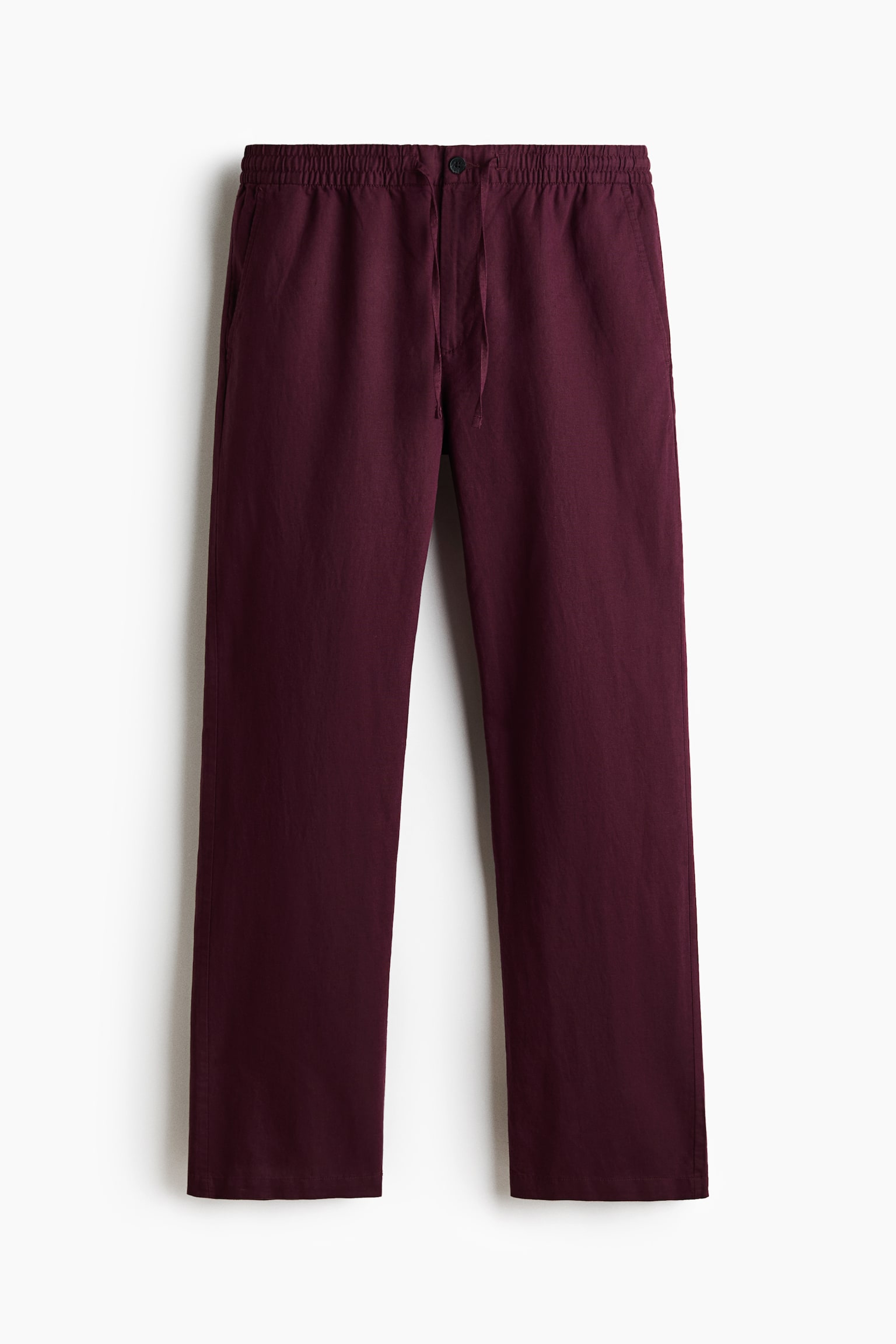 Dark red trousers are presented front-facing, featuring a covered elasticated waist with a drawstring and a button detail, along with visible side pockets. The trousers are displaying a regular fit and a subtly textured fabric. - 1