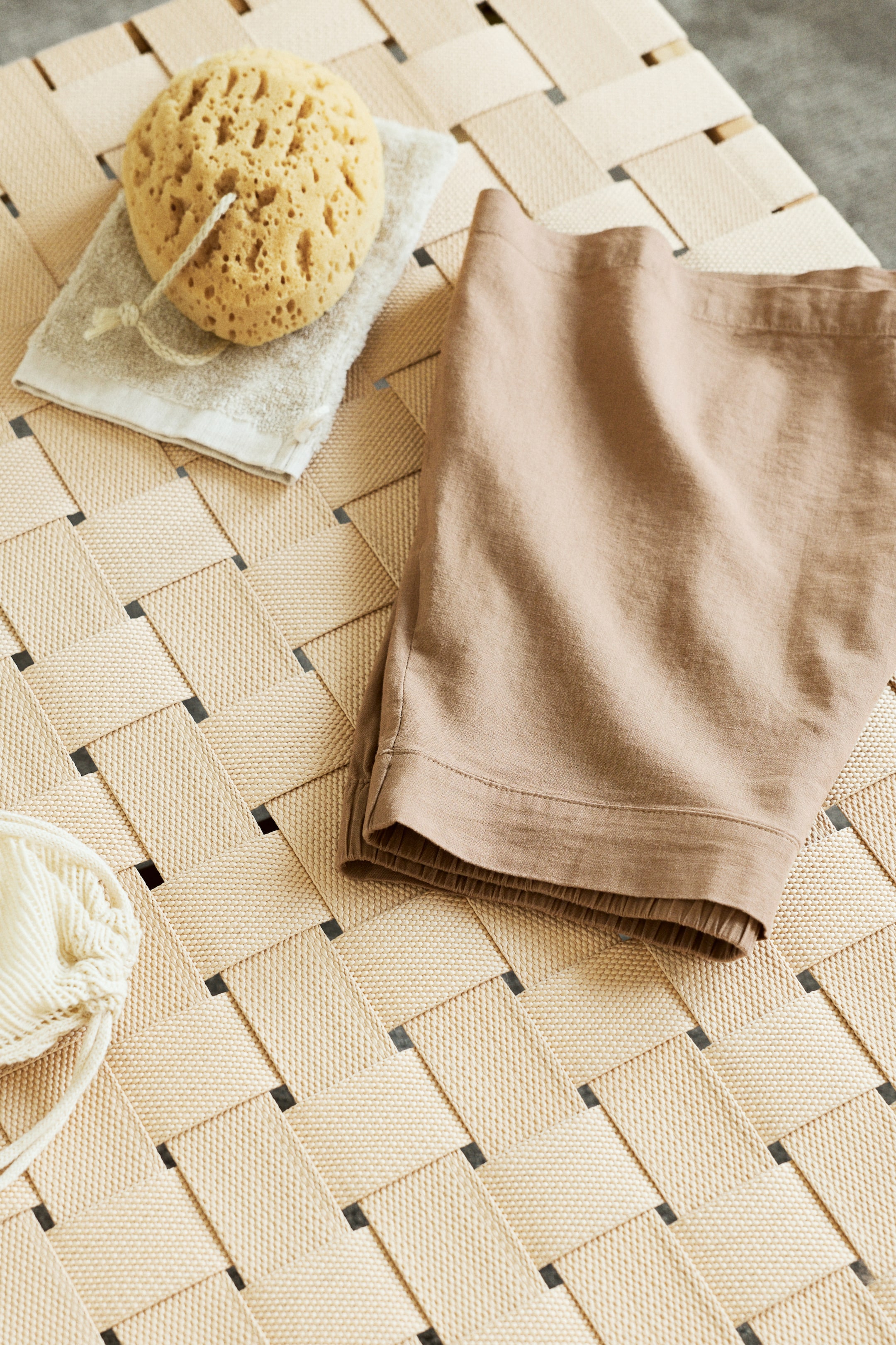 Nagyobb kép megtekintése: Egy pár világosbarna rövidnadrág van bemutatva, hajtogatva, jobbra lefelé szögelve. Lapos derékpántot és gumírozott lábszárakat mutat, látható gyűrött szövet textúrával.