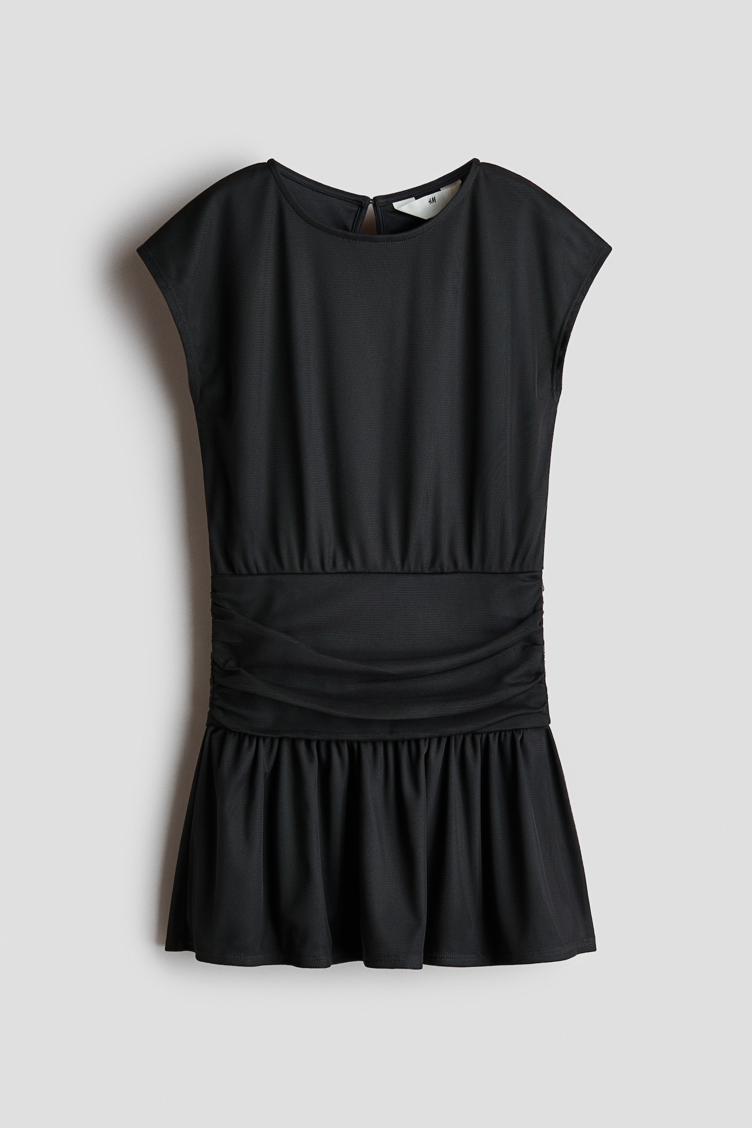 A black sleeveless top is shown from the front, featuring a round neckline, cap sleeves, a wide ruched waistband, and a flared peplum hem. The lightweight fabric gathers softly at the waist and shoulders, creating a draped effect across the midsection.