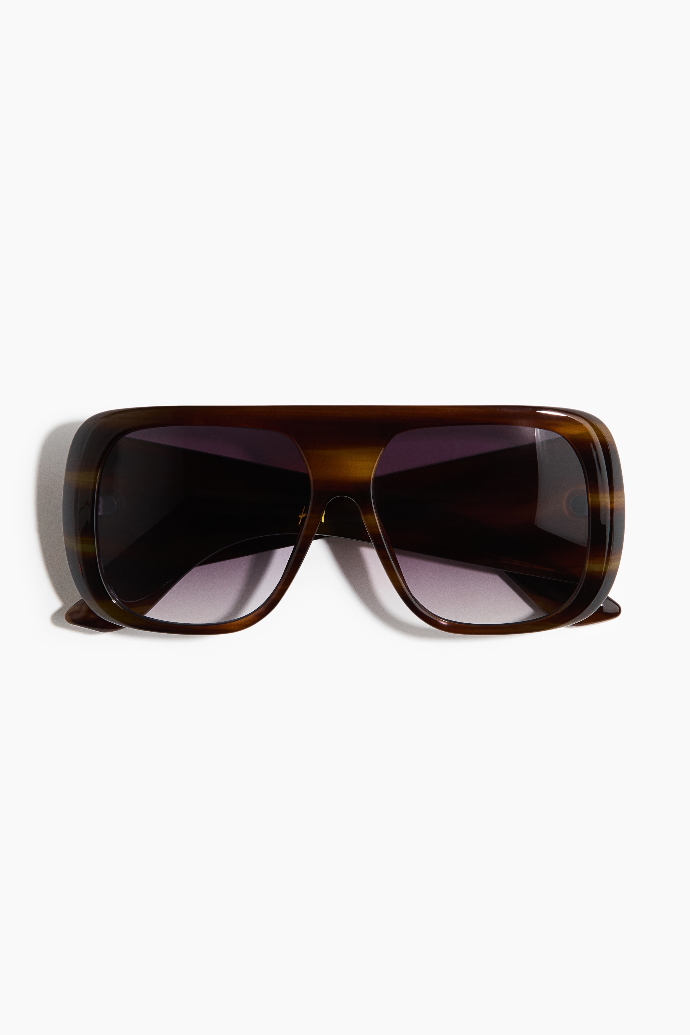 Shield sunglasses featuring thick, tortoiseshell-patterned plastic frames and light purple-tinted lenses are shown from an angled front view. The oversized design displays wide temple arms and a flat-top bridge.