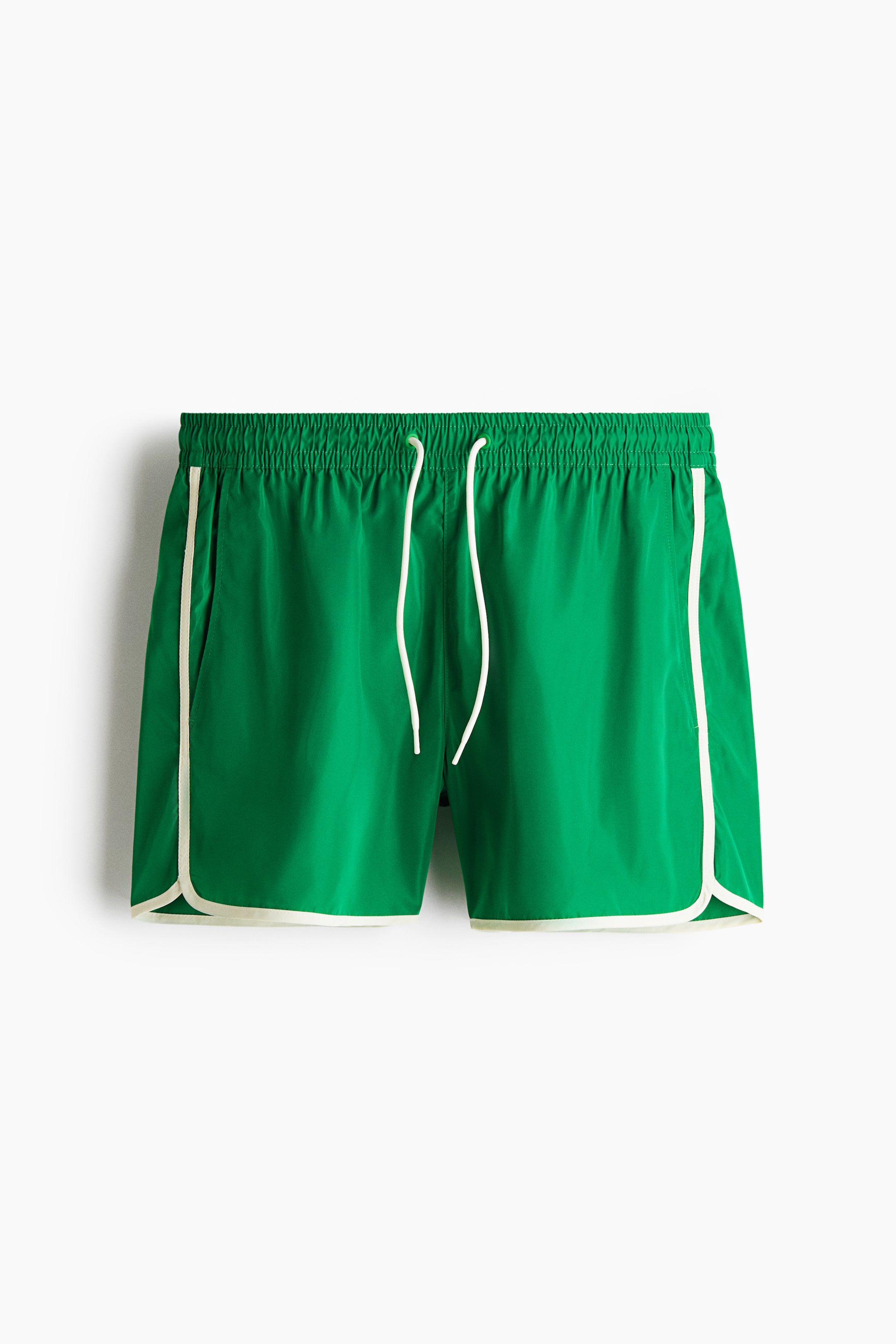 View larger image: Green shorts are shown from the front, highlighting an elastic, ruched waistband with white drawstrings. White piping outlines the side pockets and curves around the leg openings.