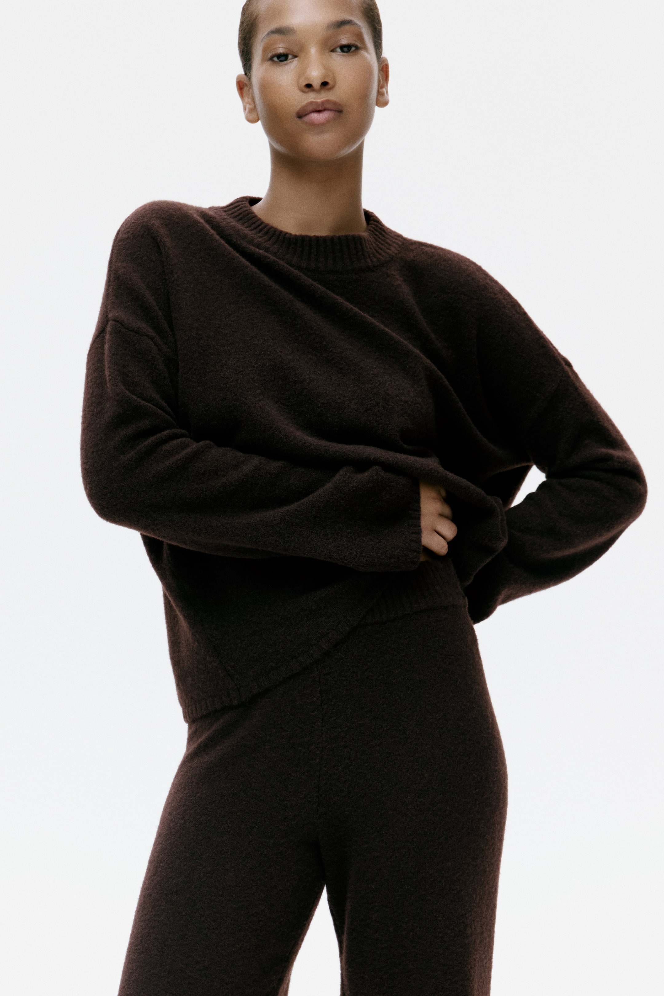 View larger image: A dark brown, fuzzy-knit sweater and matching trousers are shown from the front. The sweater features a relaxed fit, crew neck and ribbed trim, while the coordinating trousers present a comfortable, straight silhouette.