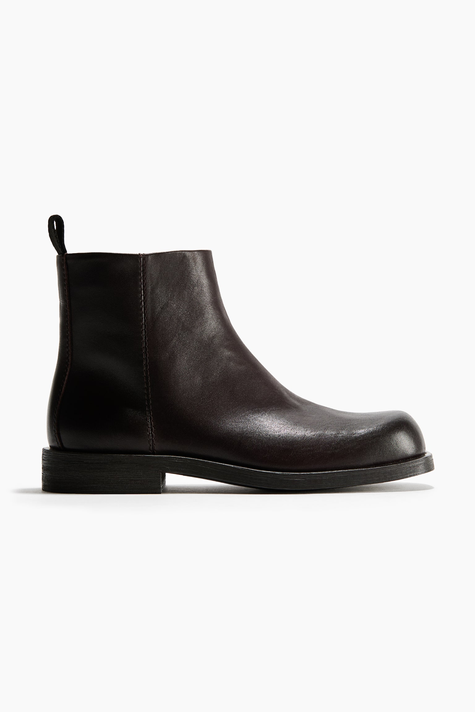 A dark brown leather ankle boot is resting in side profile facing right, showcasing its smooth leather upper, rounded toe, and low block heel. The boot features a thick dark sole, subtle vertical stitching on the side panel, and a pull tab at the rear collar.