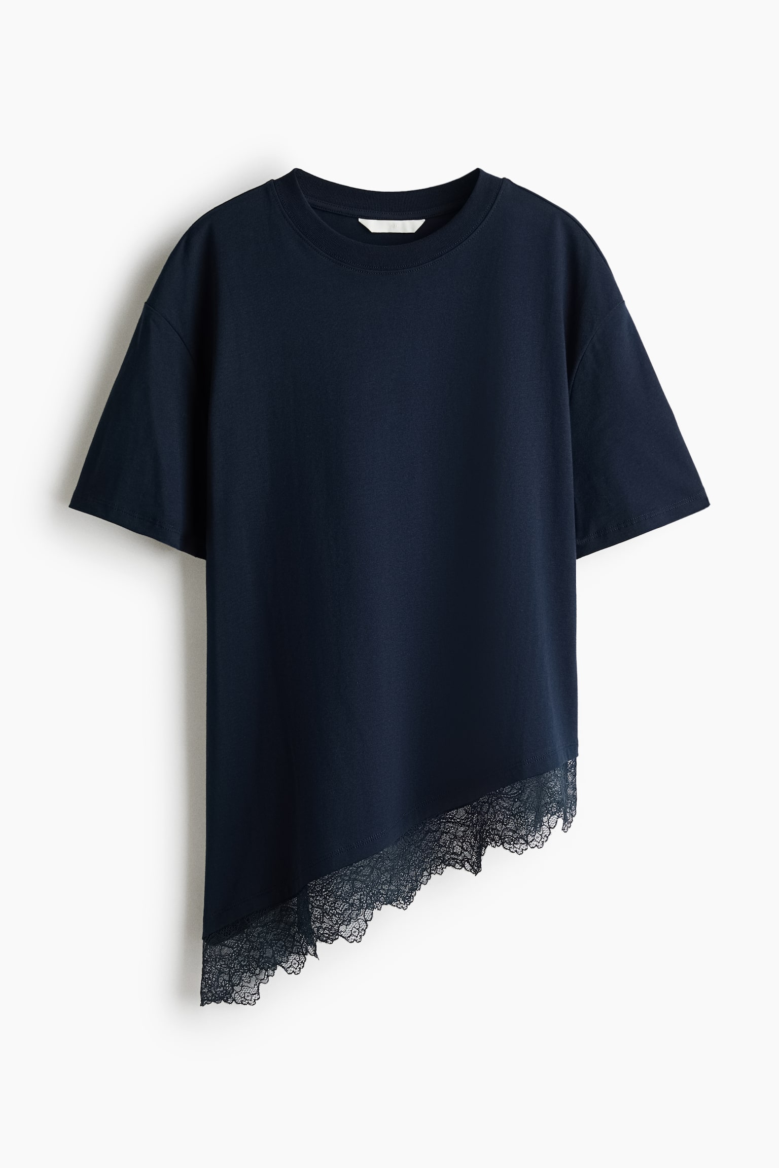 A dark navy blue relaxed-fit T-shirt is shown from the front, featuring a ribbed crew neck, dropped shoulders, and short sleeves. The T-shirt is designed with an asymmetrical hemline sloping diagonally and finished with a matching scalloped lace trim.