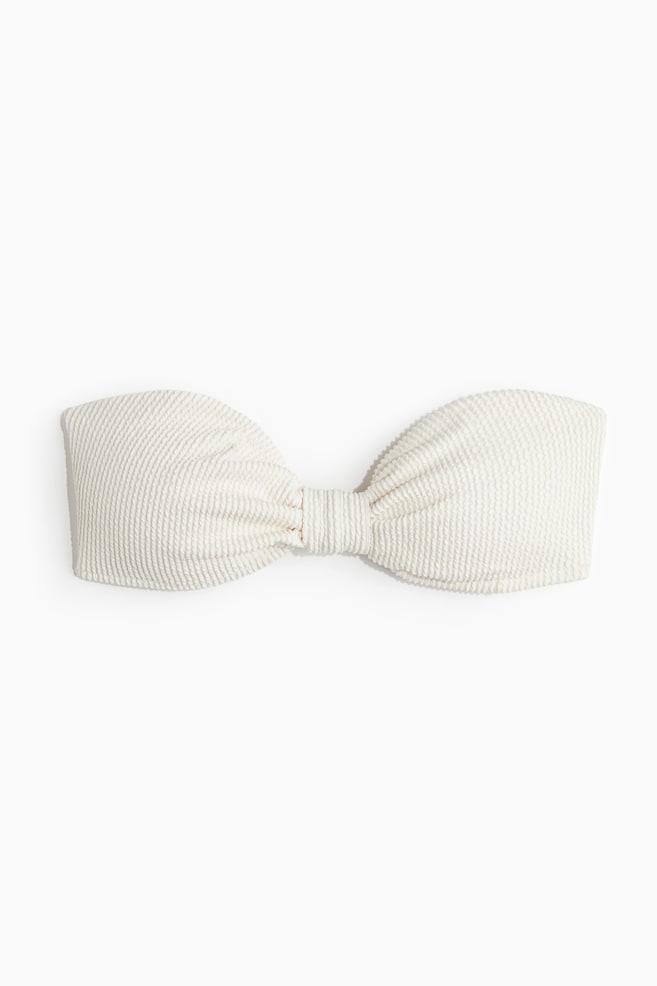 El top bandeau blanco se muestra de FRENTE, con una textura acanalada arrugada. Un nudo central prominente forma el diseño, con paneles estructurados que se extienden horizontalmente desde él. - 1